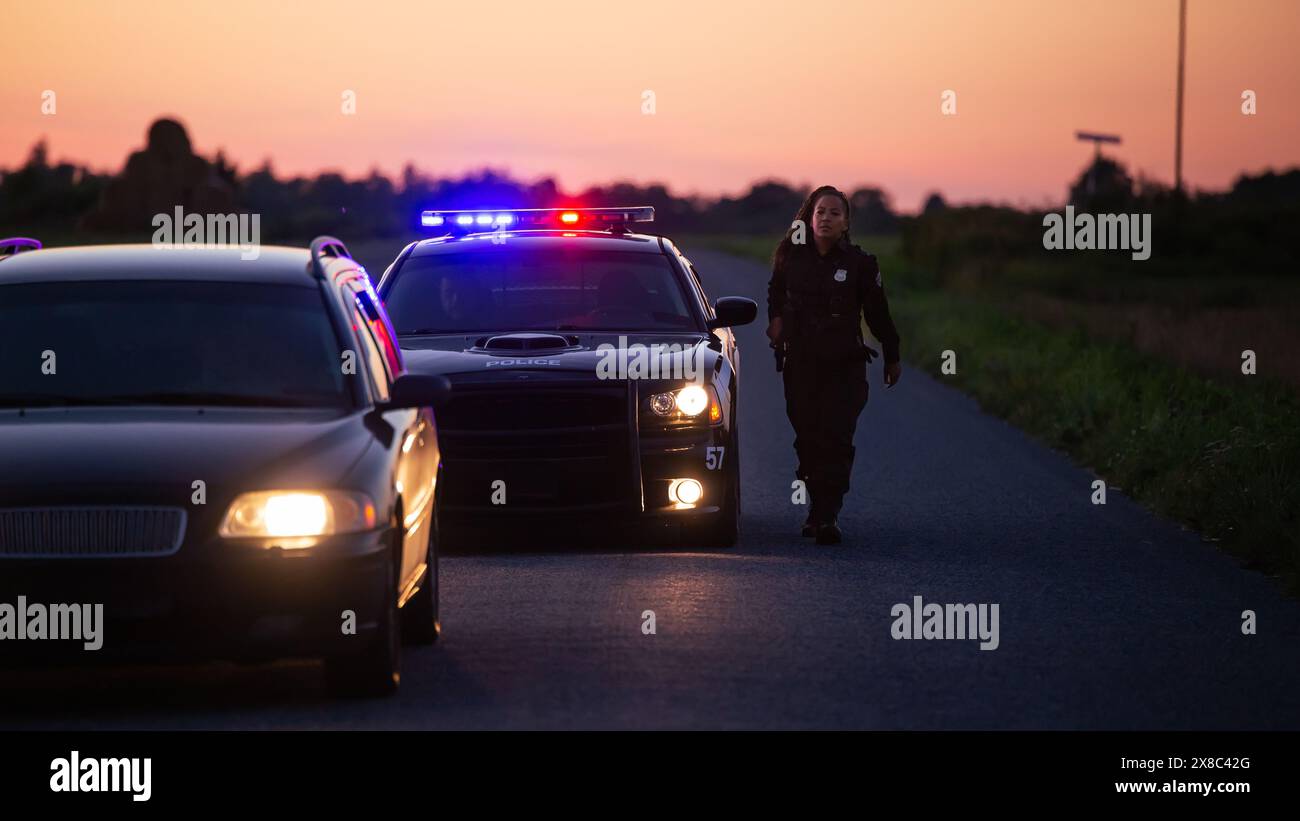 Der Highway Traffic Patrol Car fährt über das Fahrzeug auf der Straße. Der männliche Polizeibeamte kommt und bittet den Fahrer um einen Führerschein und eine Registrierung. Angestellter des Gesetzes, der beruflich Arbeit leistet. Weitwinkelaufnahmen Im Kinoformat Stockfoto