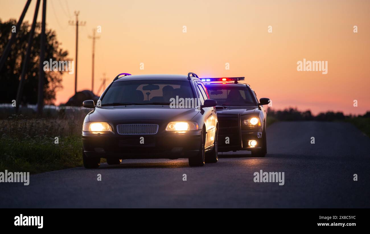 Der Rasende Fahrer Wird Von Einem Polizeiwagen Angehalten. Der Weitschuss der beiden Autos hielt in einer Road Crossing an Open Field. Betrunkener Fahrer wird von professionellen Offizieren erwischt Stockfoto