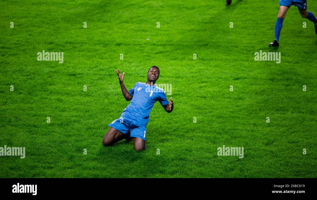 Meisterschaftsspiel: Blue Soccer Team Attack, Spieler Run Happy After Scoring Goal, Feier Sieg, rutsche auf Knien. Sport Channel Broadcast Tv Konzept. Stockfoto