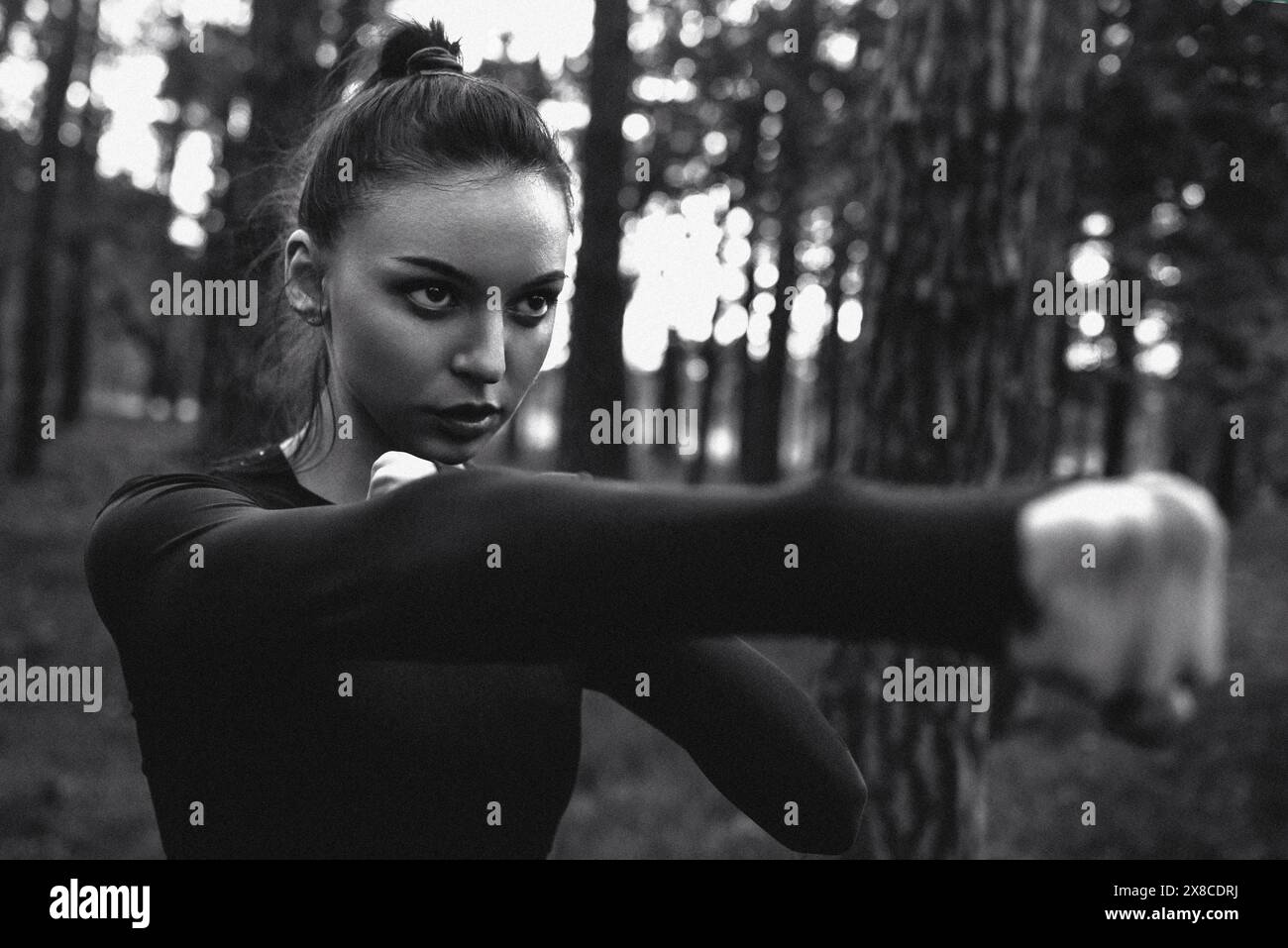 Schwarz-weiß-Foto einer Frau, die in der Natur Kampfkunst übt. Filmmarnungseffekt Stockfoto