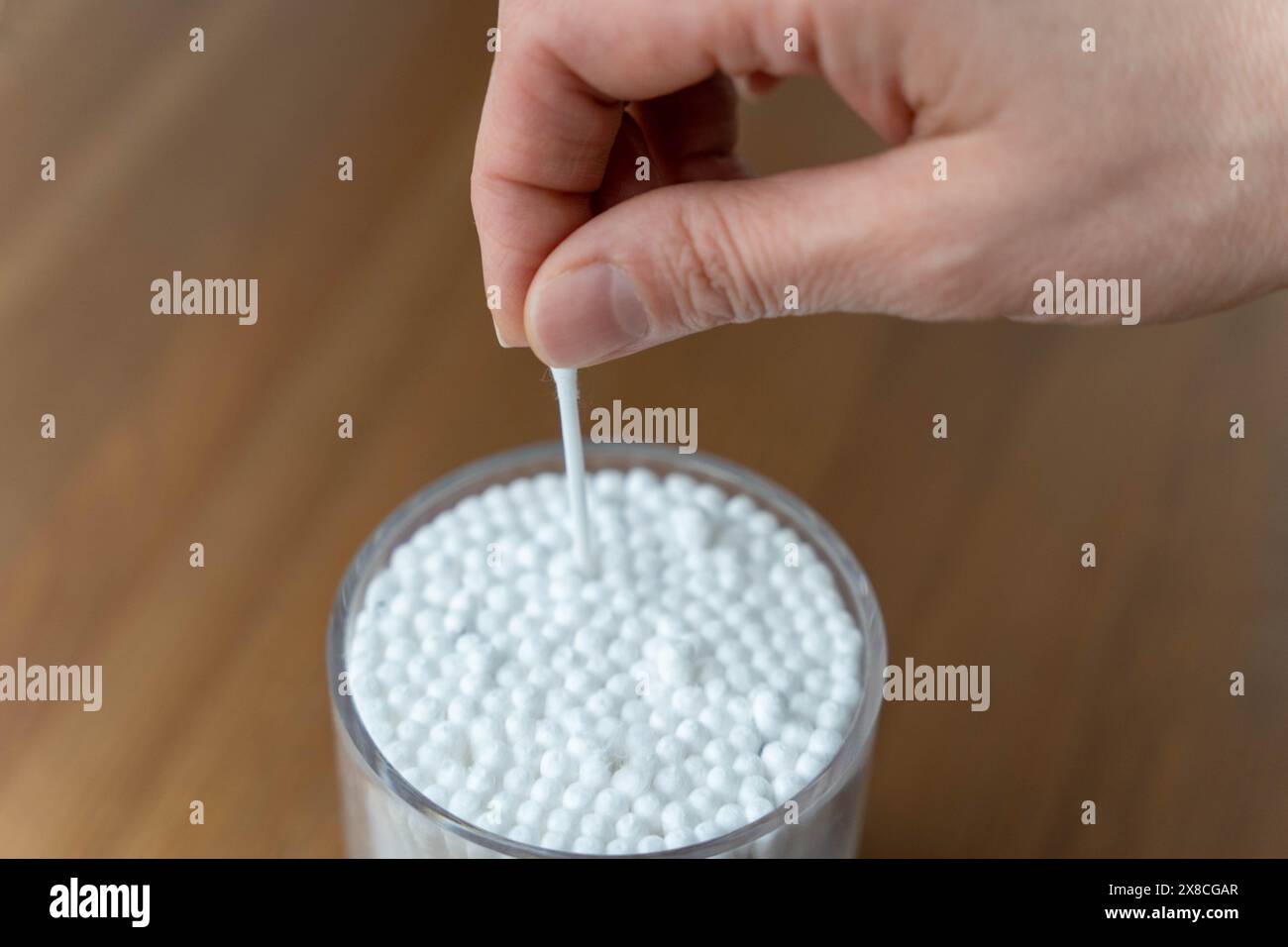 Nahaufnahme einer weiblichen Hand, die einen Wattestäbchen aus einem Behälter hält und die persönliche Hygiene und Gesundheitspraktiken hervorhebt. Das Bild konzentriert sich auf Cleanli Stockfoto