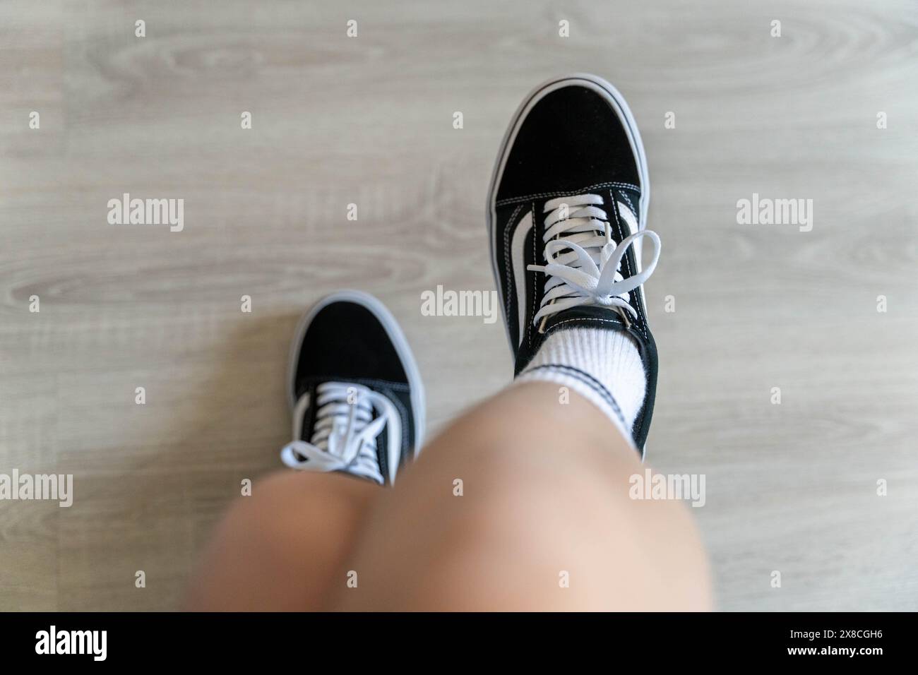 Eine Person, die mit schwarzen und weißen Schuhen auf den Füßen steht. Stockfoto
