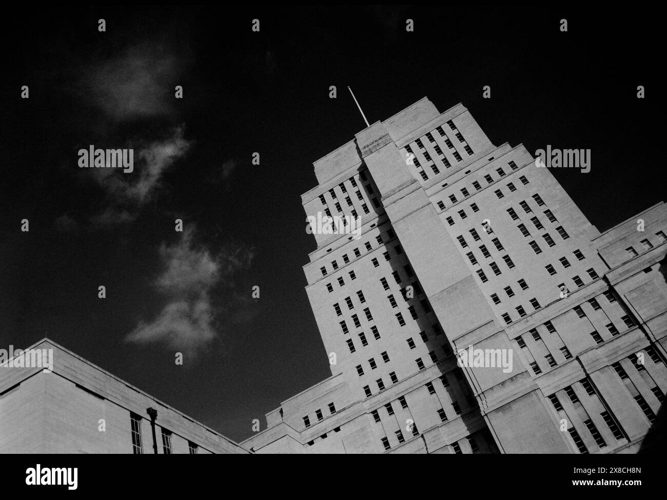 Senate House University of London, London England Senate House ist das Verwaltungszentrum der University of London im Herzen von Bloomsbury, London, direkt nördlich des British Museum. Das Art déco-Gebäude wurde zwischen 1932 und 1937 als erster Bauabschnitt eines großen, unvollendeten Bauprojekts errichtet, das Charles Holden für die Universität entwarf. Er besteht aus 19 Etagen und ist 210 Fuß (64 m) hoch. Während des Zweiten Weltkriegs inspirierte die Nutzung des Gebäudes durch das Informationsministerium zwei Werke englischer Schriftsteller. Der erste, Graham Greenes Roman der Mini Stockfoto