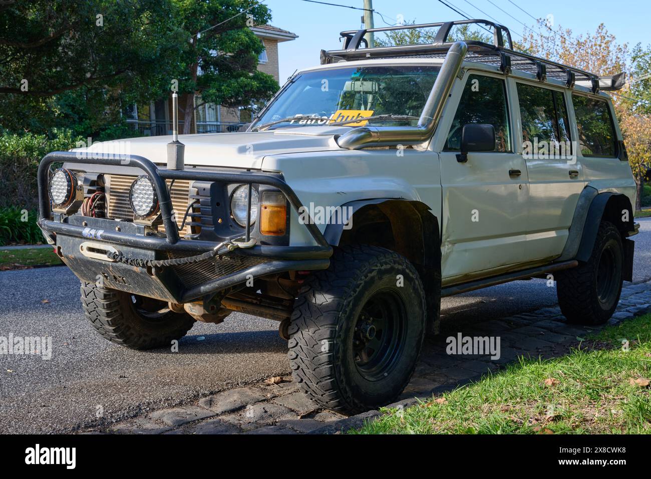 Der weiße Y60 Nissan Patrol 4x4 parkt in einer Vorstadtstraße, modifiziert für den Geländeeinsatz und mit verschiedenen Zubehörteilen an einem sonnigen Tag Stockfoto