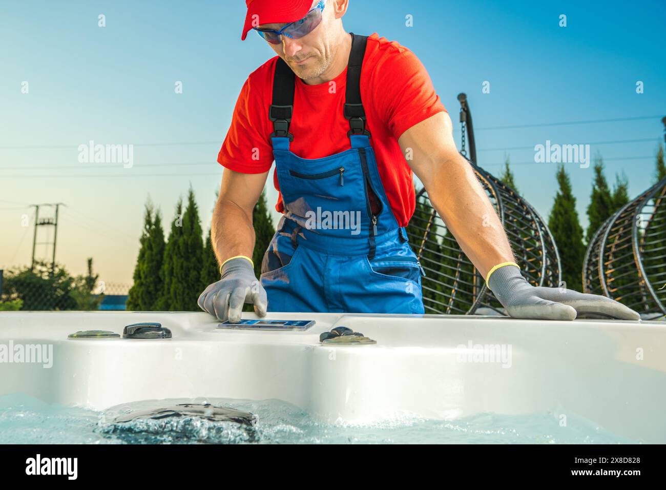 Der Arbeiter schrubbt und reinigt einen Whirlpool im Hinterhof. Stockfoto