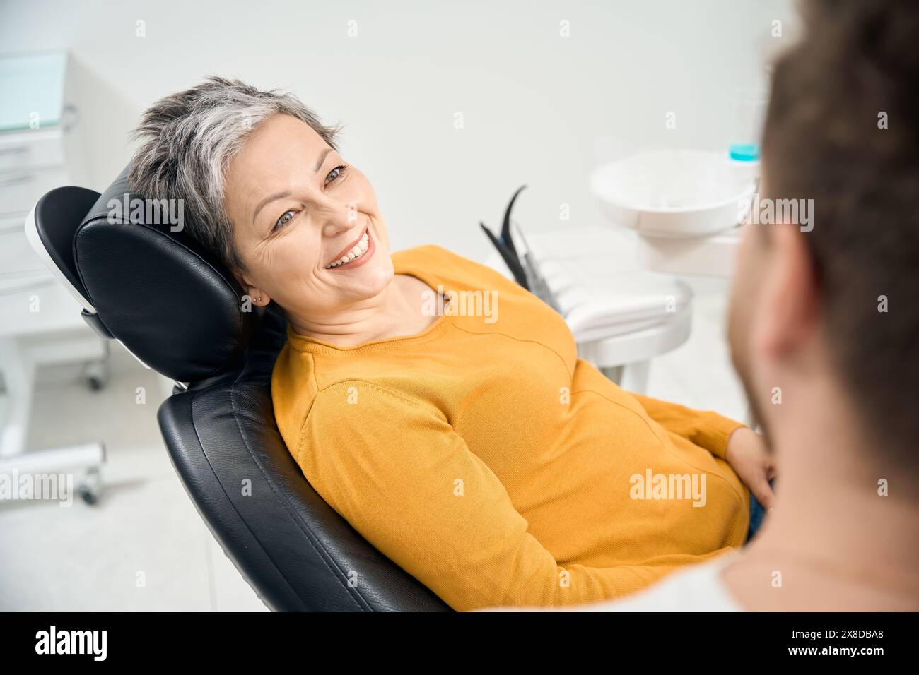 Frau Klientin in ihrem 50, die einen Arzt Stomatologen ansieht und lächelt Stockfoto