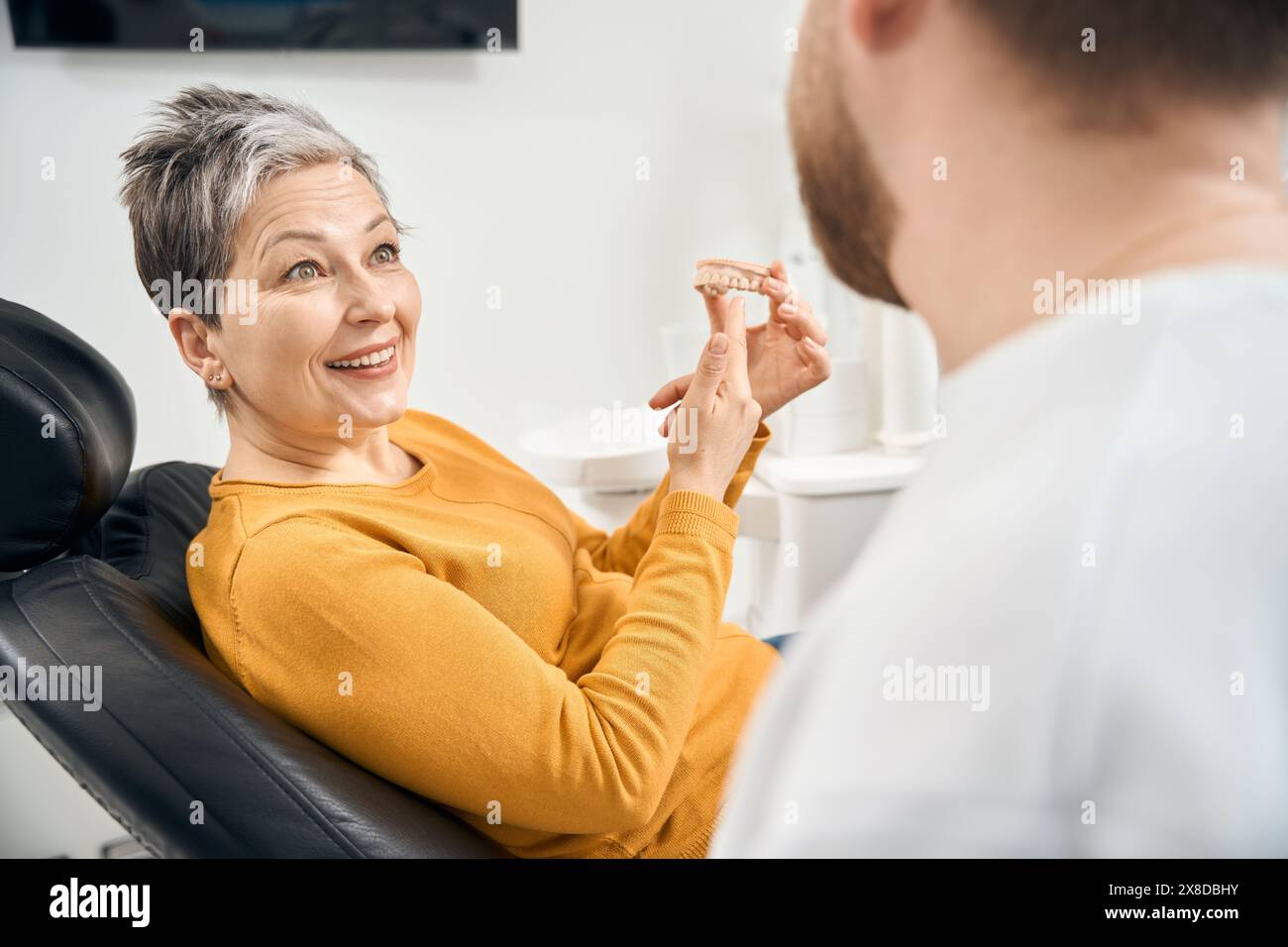 Überraschte Frau, die in den Händen hält 3D-Modell ihrer oberen Zähne Stockfoto