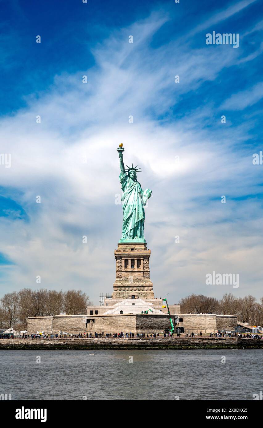 Lady Liberty macht den Weg frei! Fangen Sie das legendäre Symbol der Freiheit ein. Ihre Taschenlampe wurde hoch vor einem klaren blauen Himmel gehalten. Ideal für Reisen und historische Inhalte. Stockfoto