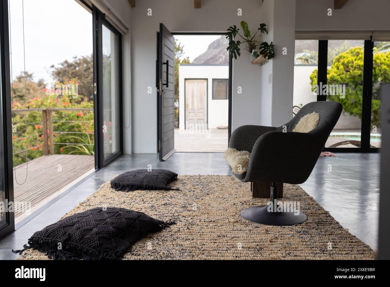 Zu Hause, zwei schwarze Sessel mit weißen Kissen, die auf offene Türen gerichtet sind Stockfoto