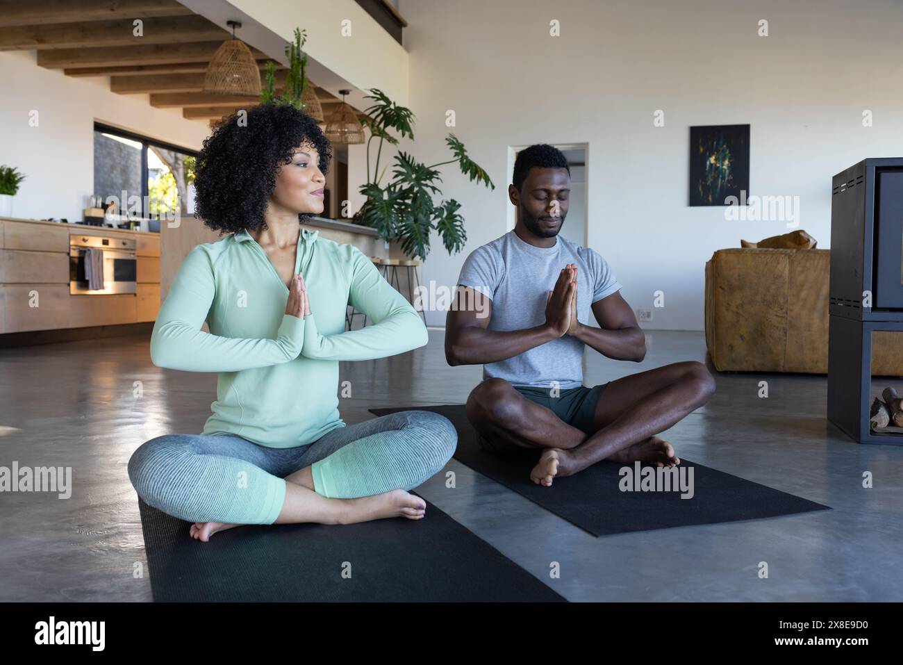 Ein vielseitiges Paar, das zu Hause Yoga praktiziert und sich auf Posen konzentriert Stockfoto