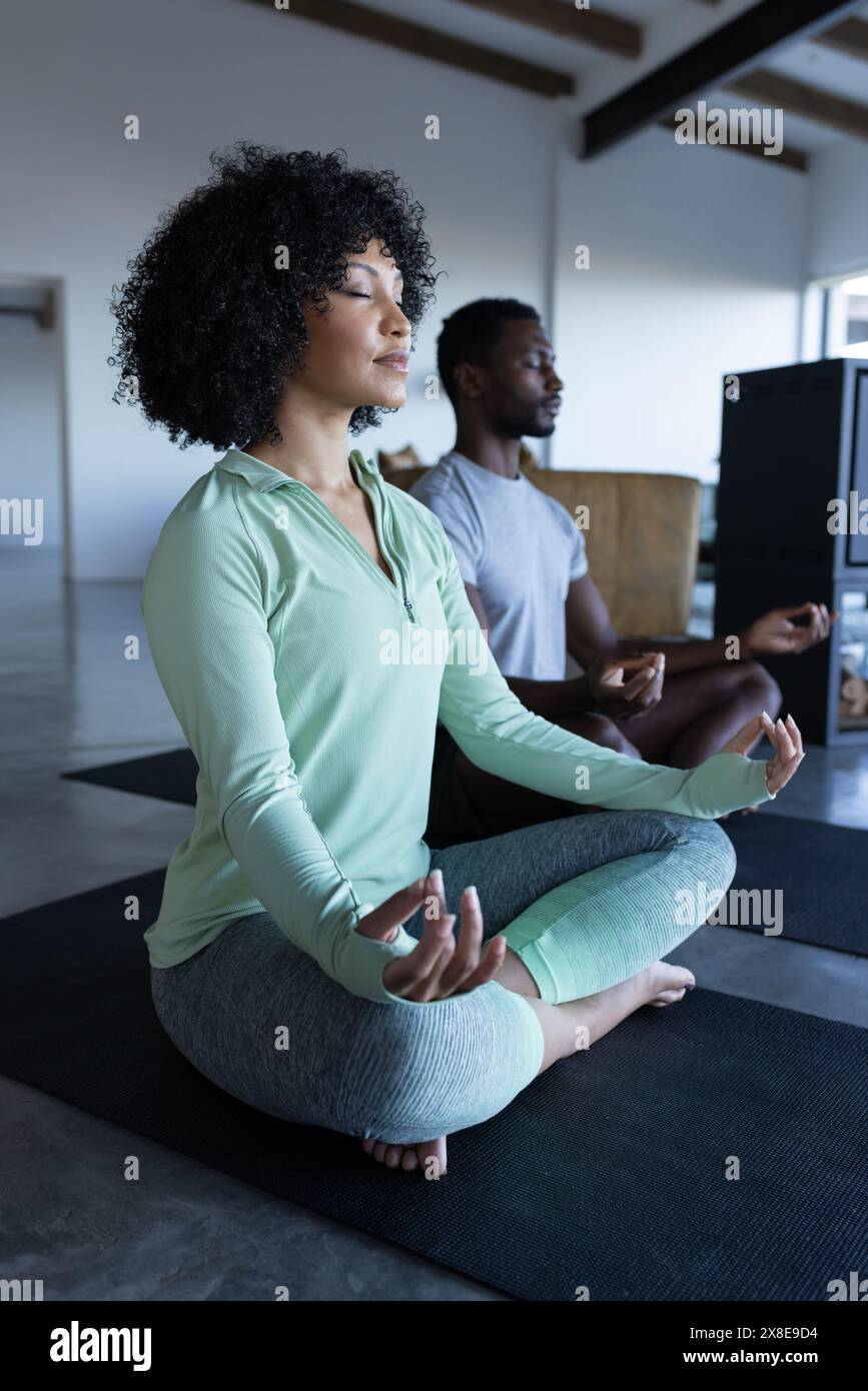 Ein vielseitiges Paar, das zu Hause meditiert, beide in lässiger Kleidung Stockfoto