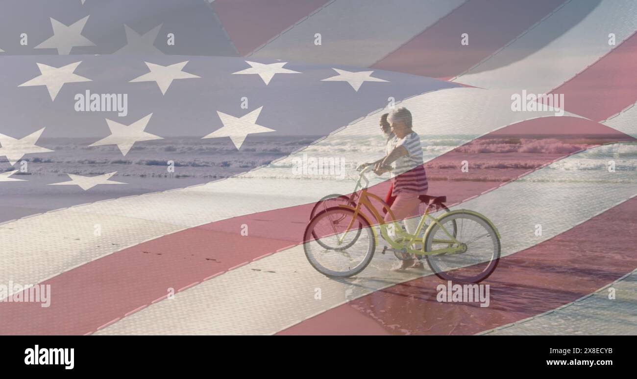 Ein junger kaukasischer Junge fährt am Strand Fahrrad, mit amerikanischer Flagge überzogen Stockfoto
