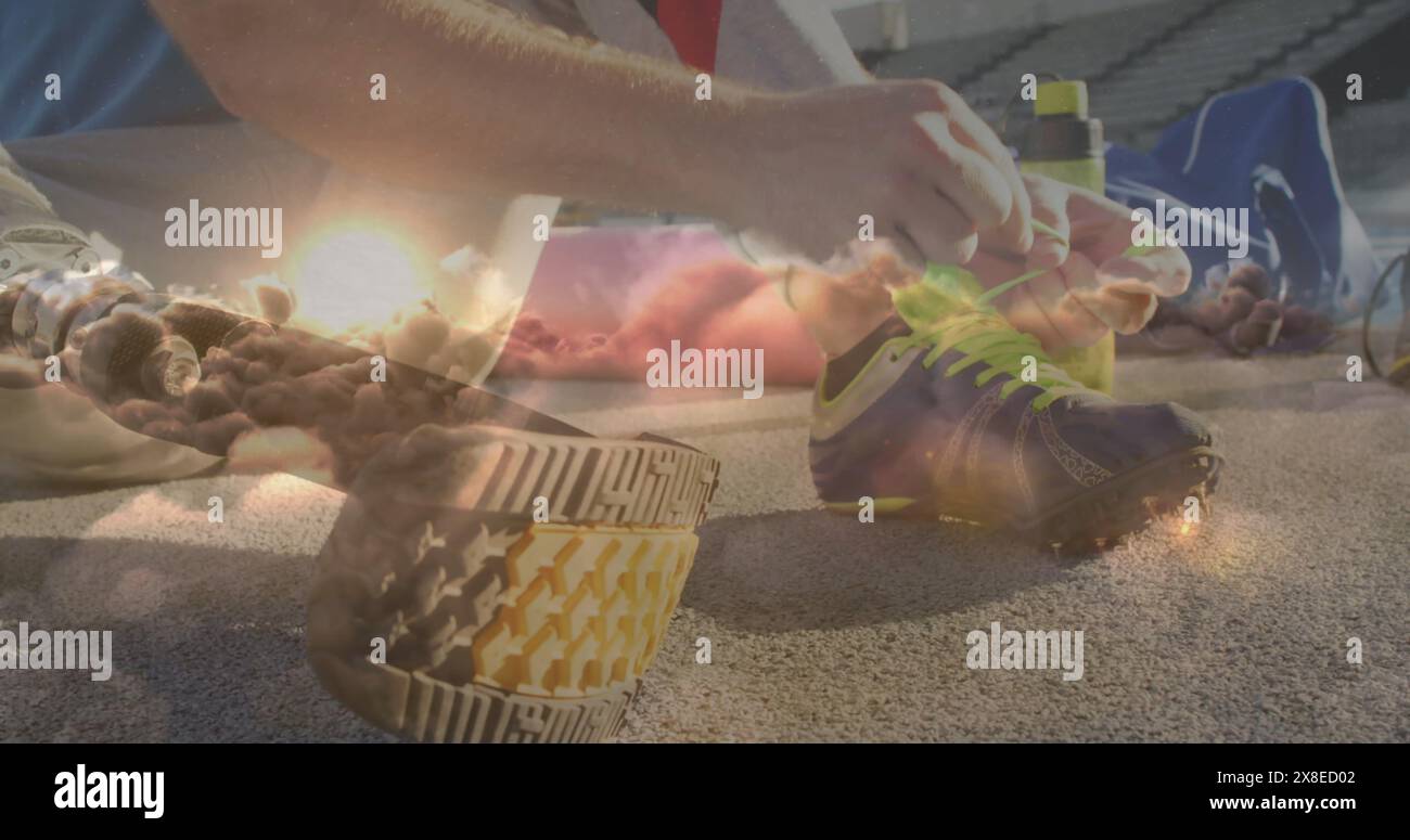 Kaukasischer Athlet, der seinen Schuh auf der Bahn bindet, umgeben von Ausrüstung Stockfoto