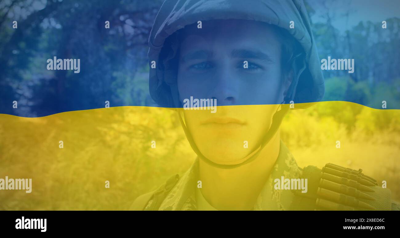 Kaukasischer junger Profi in Militäruniform steht vor ukrainischer Flagge Stockfoto
