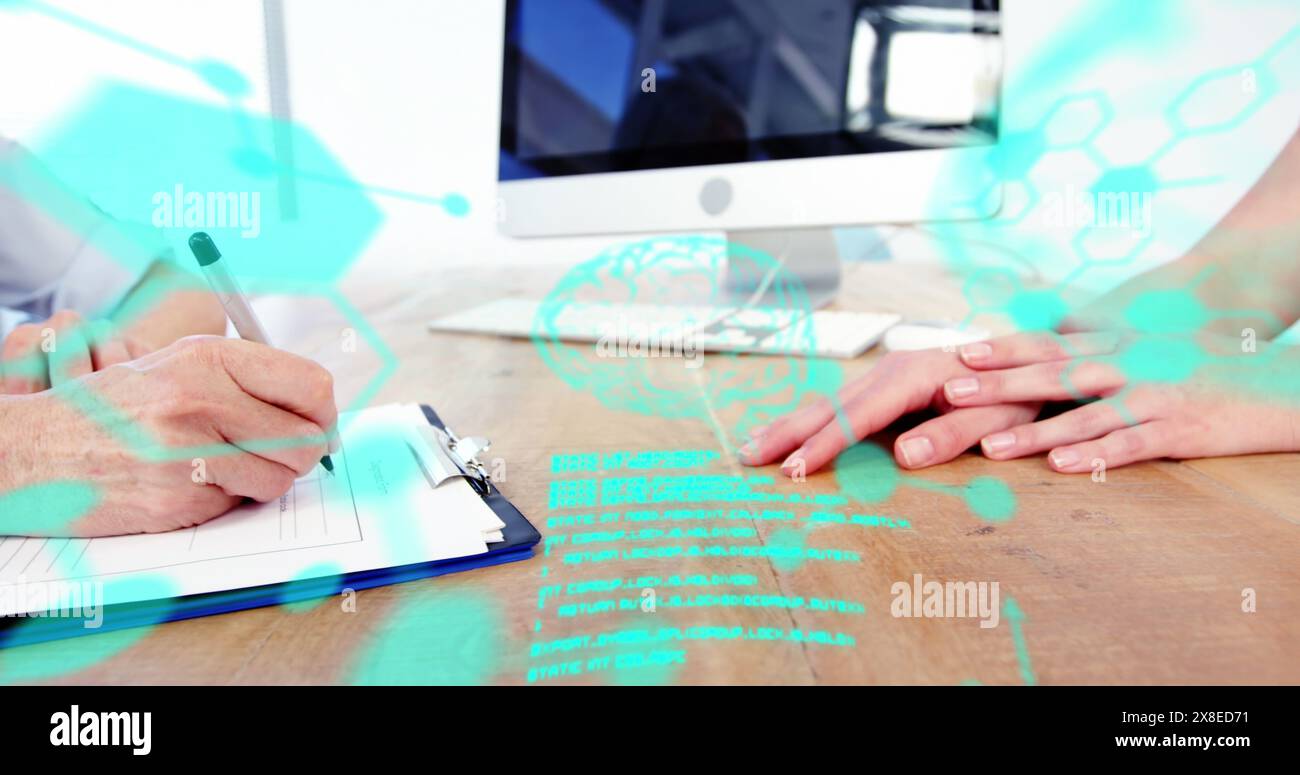 Zwei Personen am Schreibtisch, einer schreibt, der andere am Computer Stockfoto