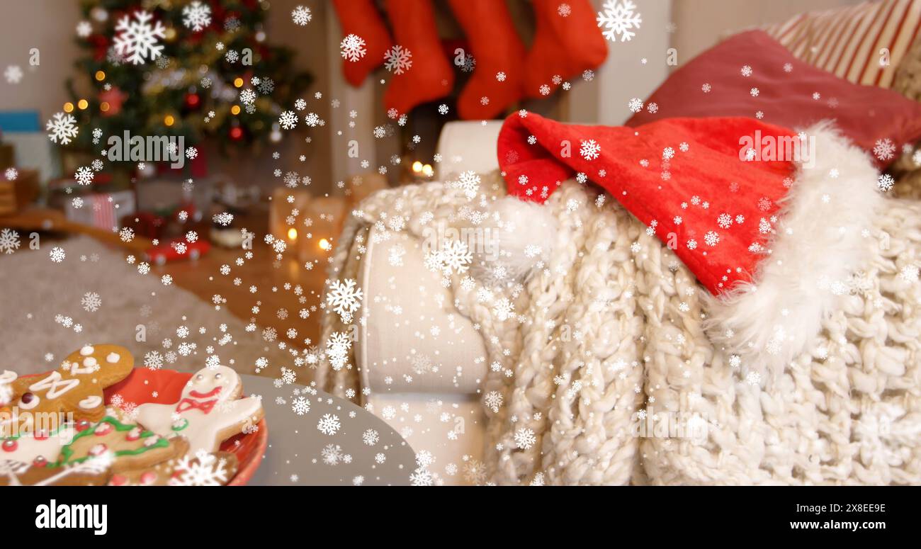 Bild von digitalen Schneeflocken, die während weihnachten auf weihnachtsmütze und Pullover auf das Sofa fallen Stockfoto