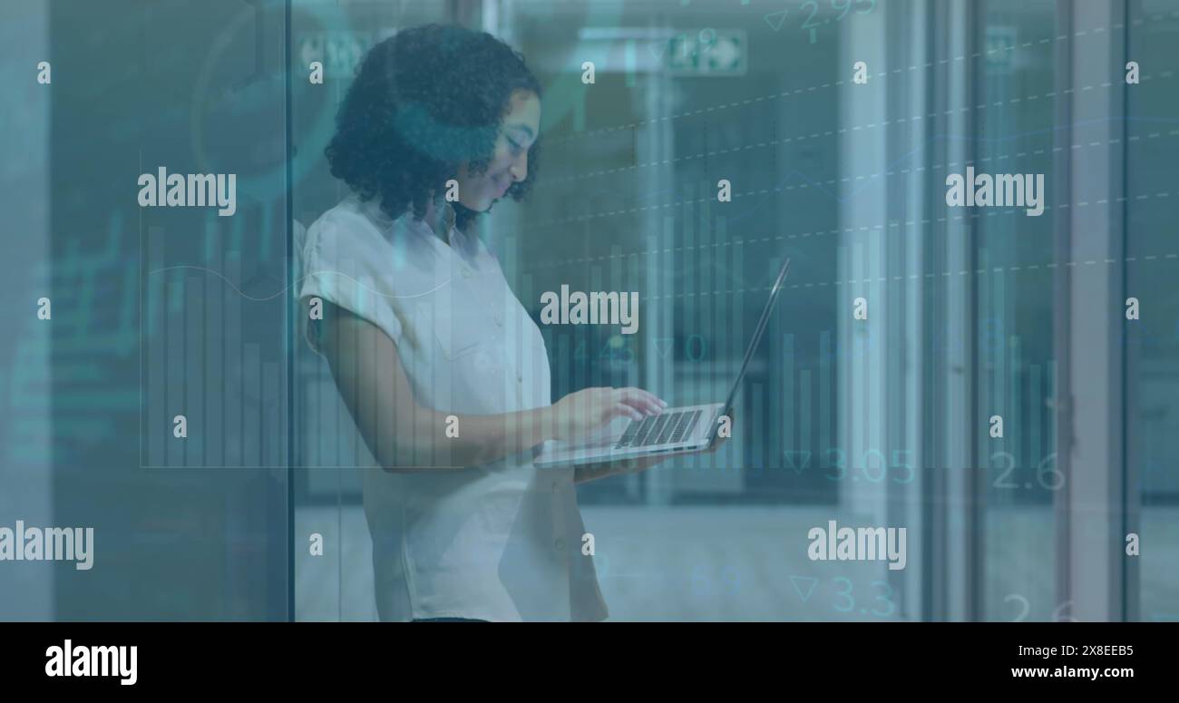 Eine glückliche Geschäftsfrau mit birassischem Charakter arbeitet spät in einem modernen Büro, sie benutzt einen Laptop, der sie benutzt Stockfoto