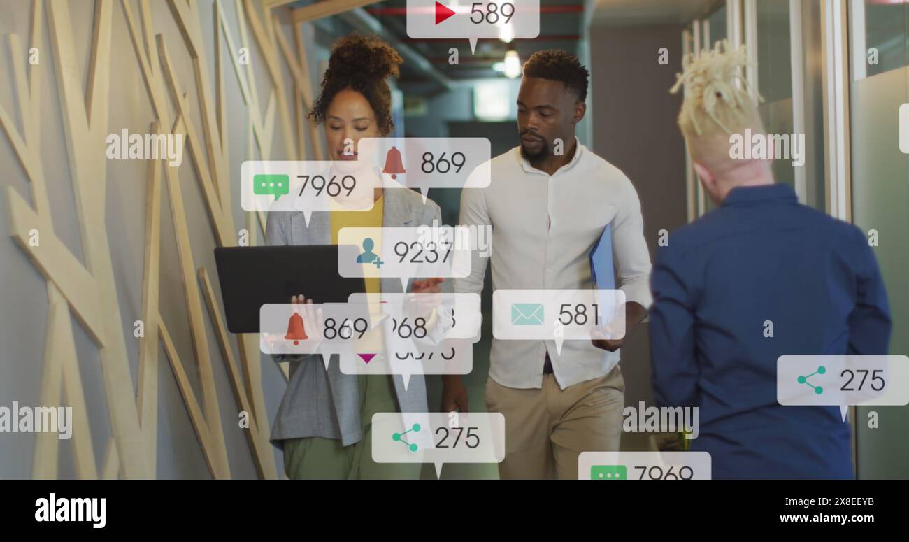 Bild von Social-Media-Ikonen über afroamerikanische Männer und Frauen, die im Büro über einen Laptop diskutieren Stockfoto