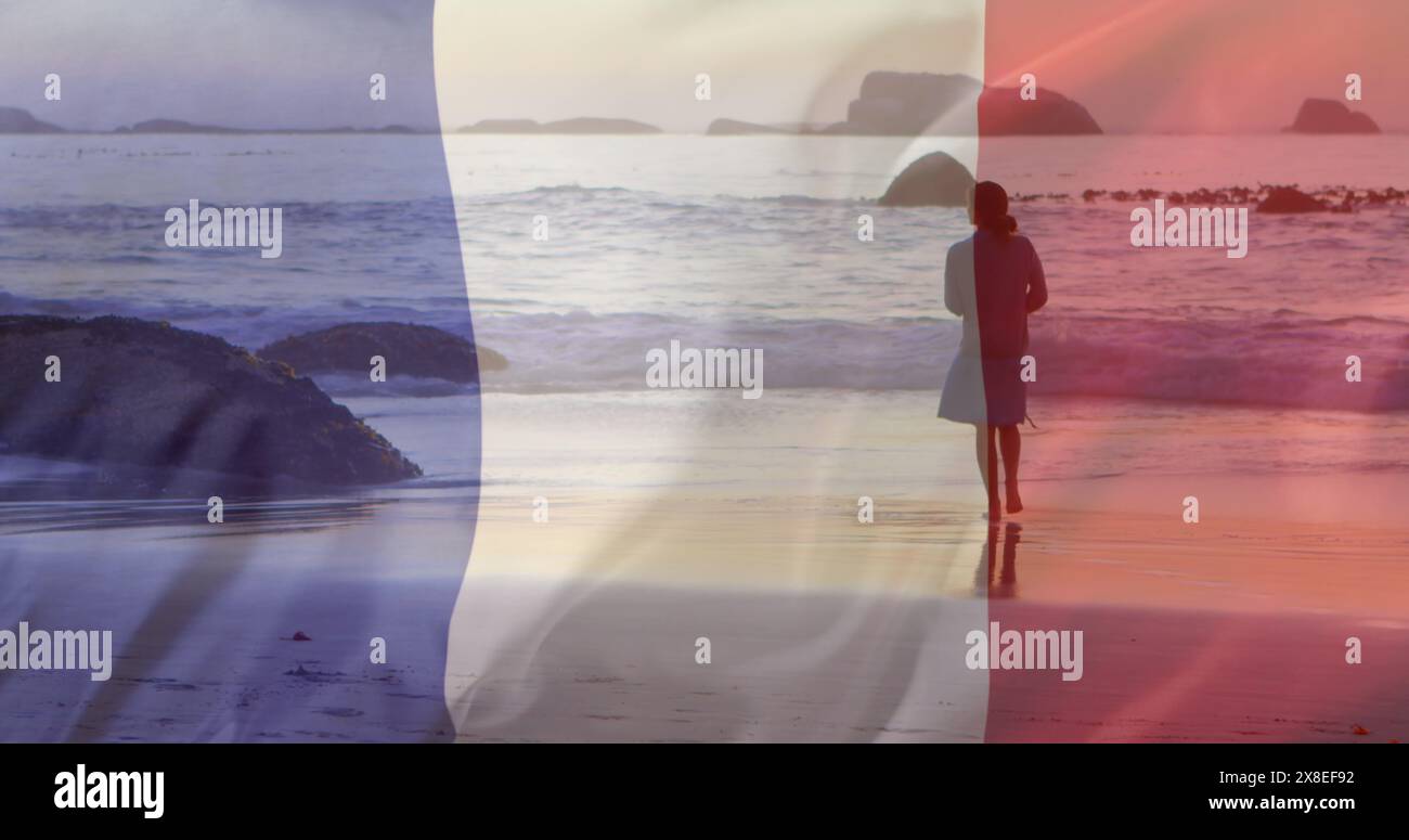 Bild der Flagge frankreichs über der kaukasischen Frau, die am Strand läuft Stockfoto