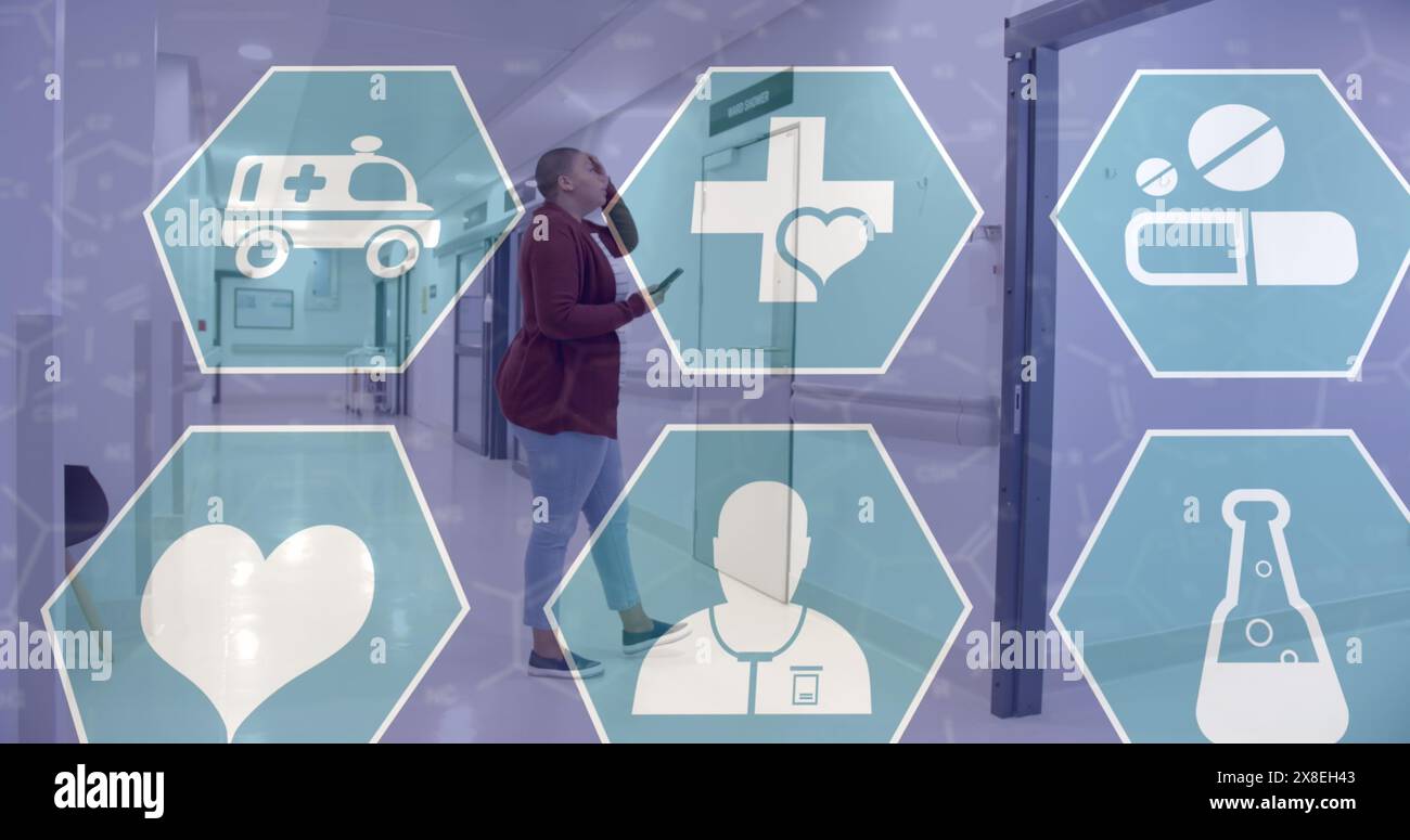 Bild mehrerer medizinischer Ikonen gegen gestresste birassische Frau im Krankenhauskorridor Stockfoto