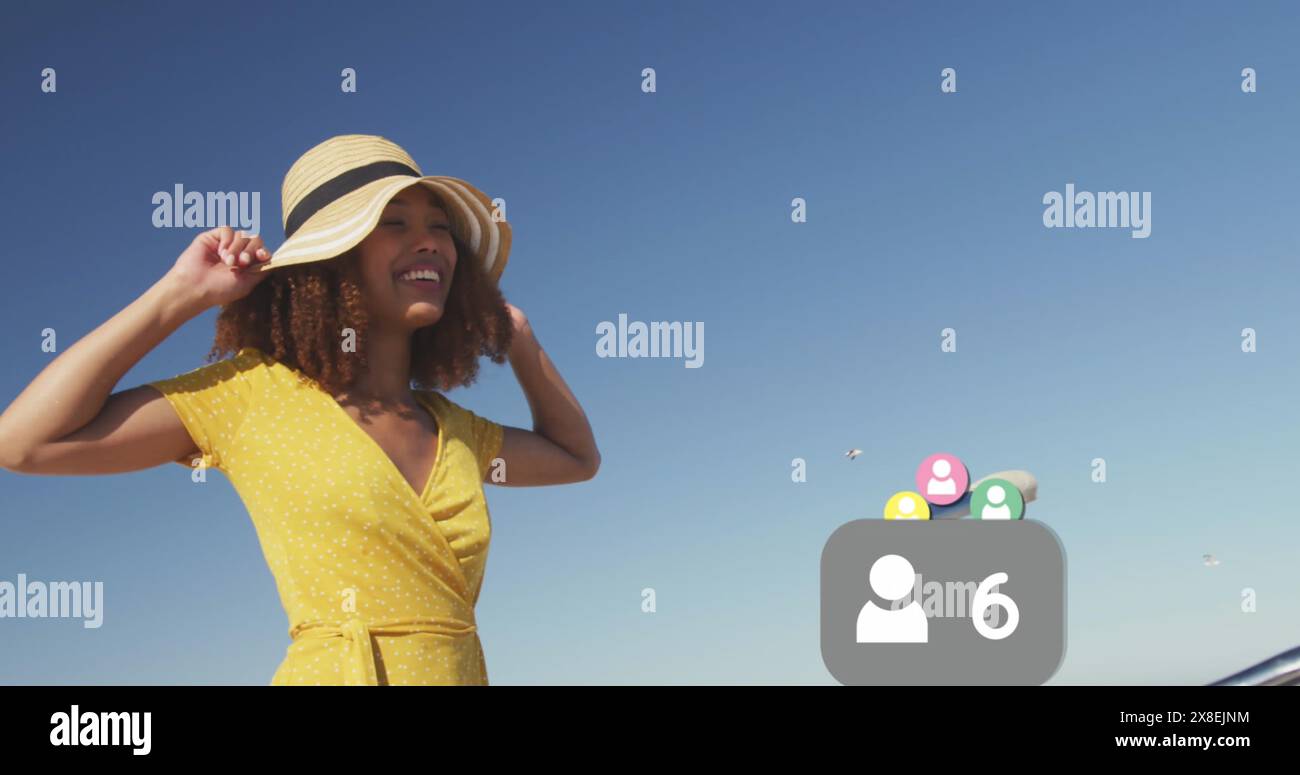 Bild von wechselnden Zahlen, Profilsymbolen, glücklicher birassischer Frau, die am Strand vor dem Himmel steht Stockfoto