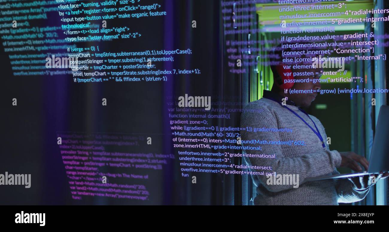 Ein Afroamerikaner in seinen frühen 30ern arbeitet an einem Laptop, umgeben von Code auf einem Bildschirm Stockfoto