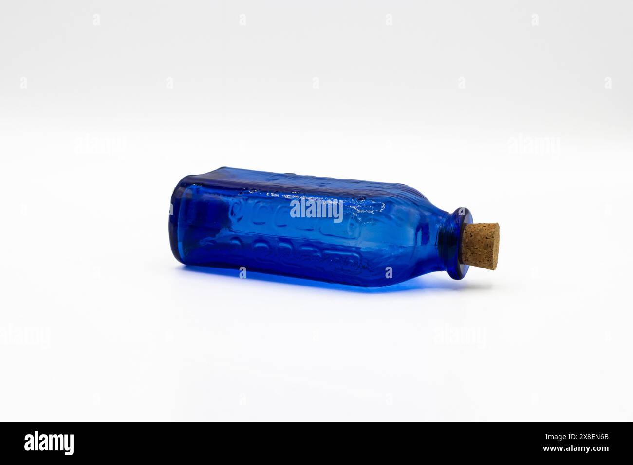 Blaue Glasflasche mit Korkdeckel auf weißem Hintergrund Stockfoto