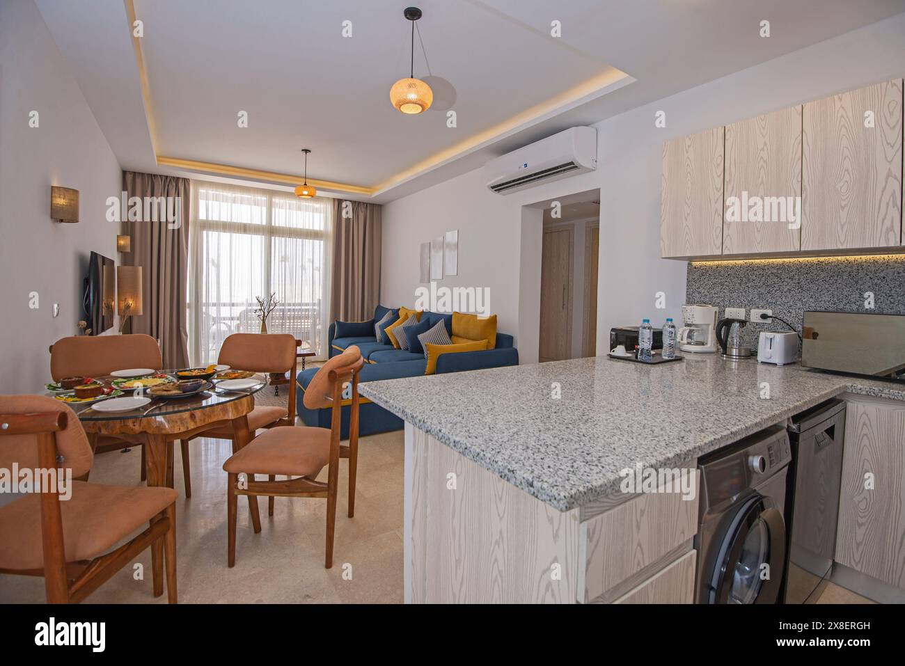 Wohnzimmer Lounge-Bereich in Luxus-Apartment Show Home zeigt Inneneinrichtung Einrichtung mit Balkon Terrasse und offene Küche Stockfoto