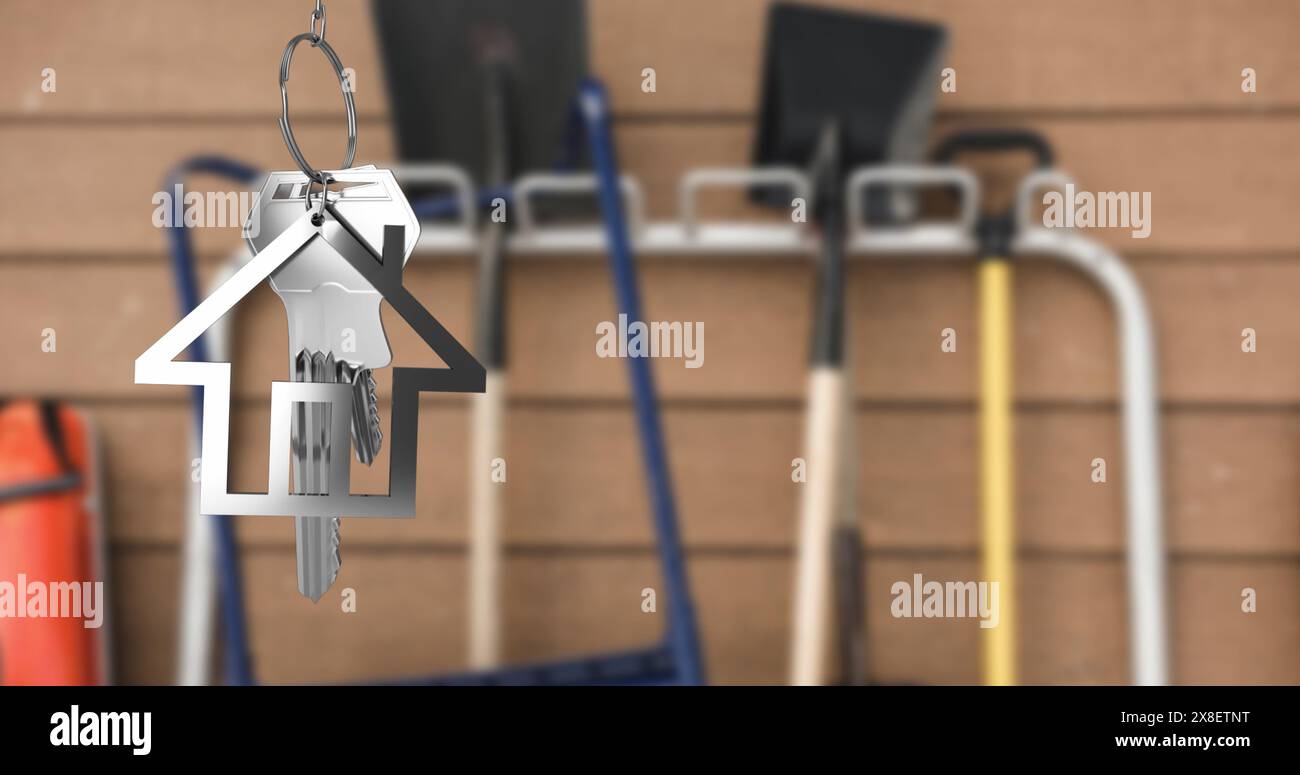 Abbildung des hängenden silbernen Hausschlüssels vor verschwommener Sicht auf die Reinigungsausrüstung Stockfoto