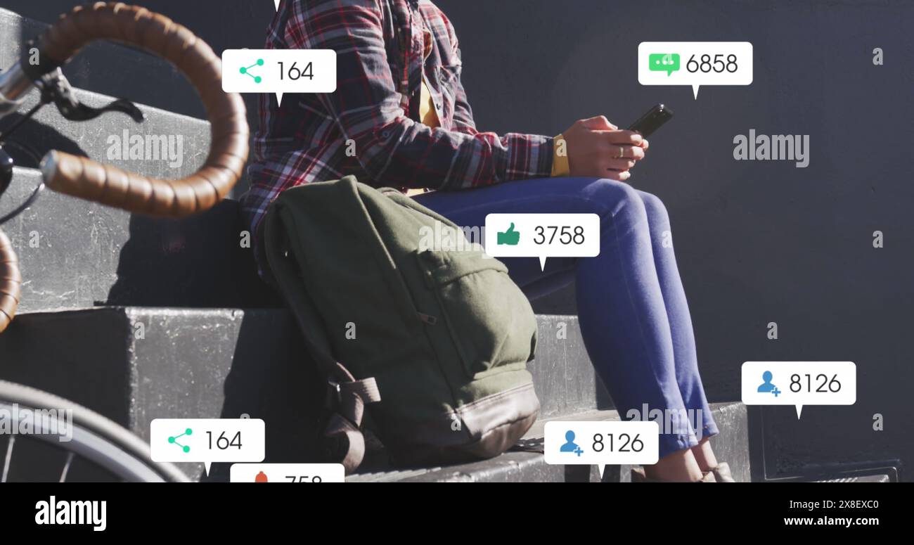 Asiatische Frau, die auf Treppen im Freien sitzt und auf das Smartphone blickt Stockfoto
