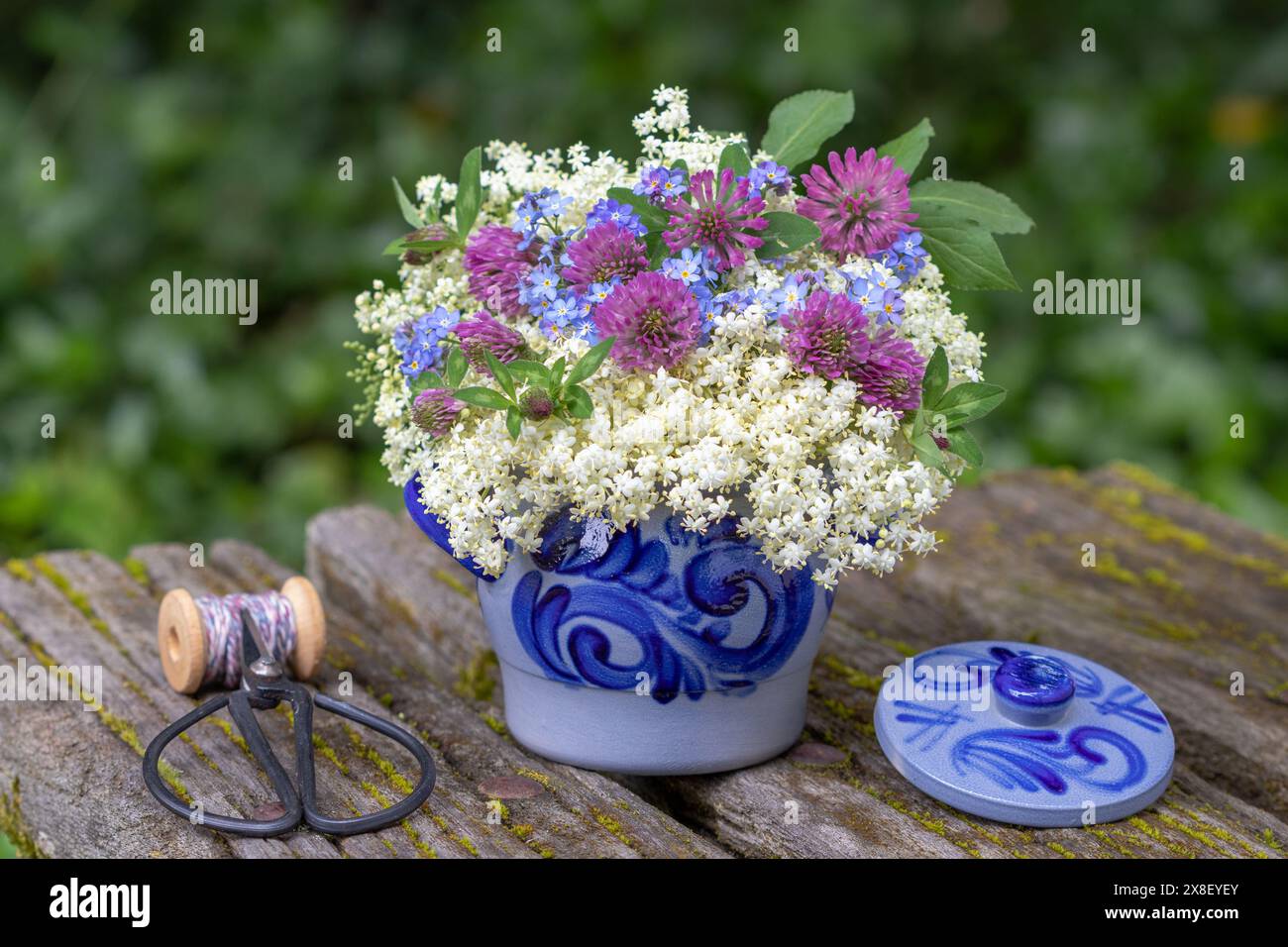 Blumenarrangements mit Holunderblüten, Klee und Vergiss mich nicht Blumen im rustikalen Topf Stockfoto