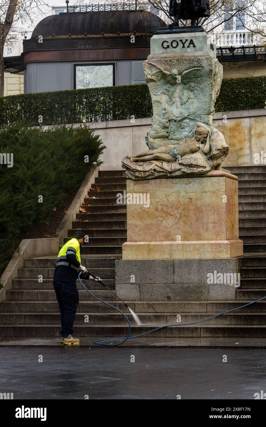 Madrid, Spanien. 12. Februar 2024: Ein Mann mit gelber Weste wäscht die Stufen vor der Francisco Goya Statue Stockfoto
