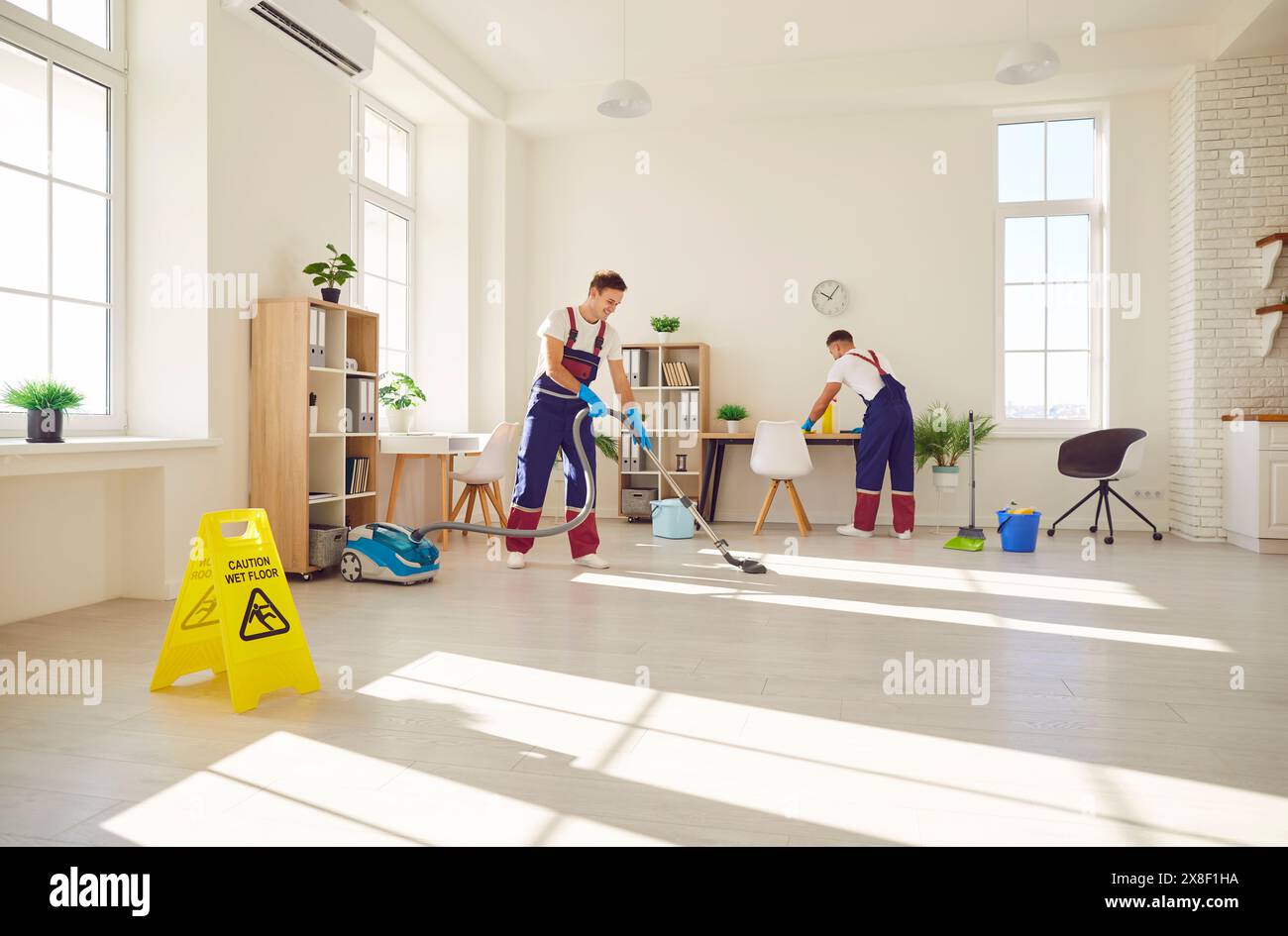 Reinigungspersonal saugen Fußboden und Staub in modernen Apartments ab Stockfoto