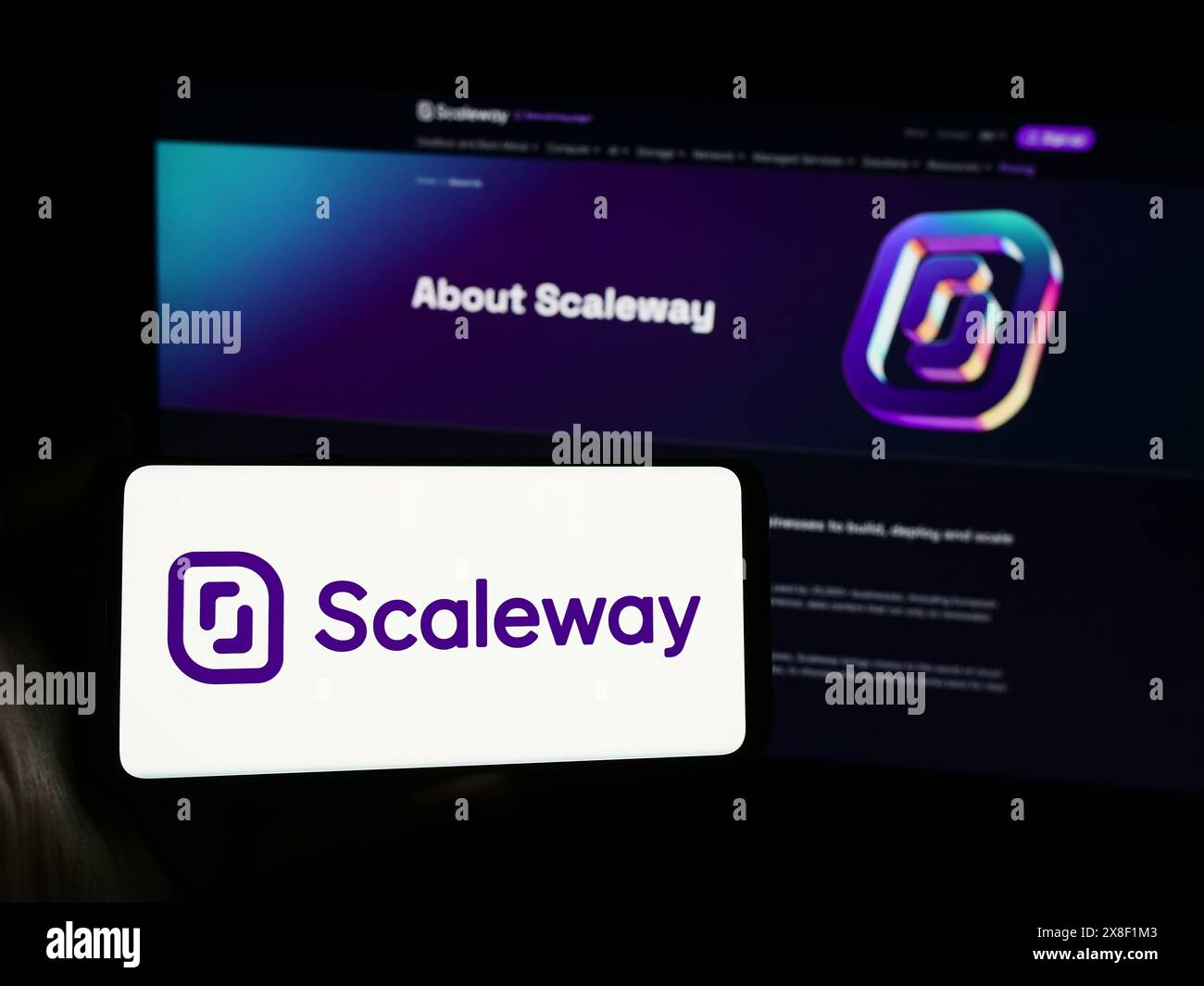 Person mit Smartphone und Logo des französischen Cloud-Computing-Unternehmens Scaleway SAS vor der Website. Schwerpunkt auf dem Display des Telefons. Stockfoto