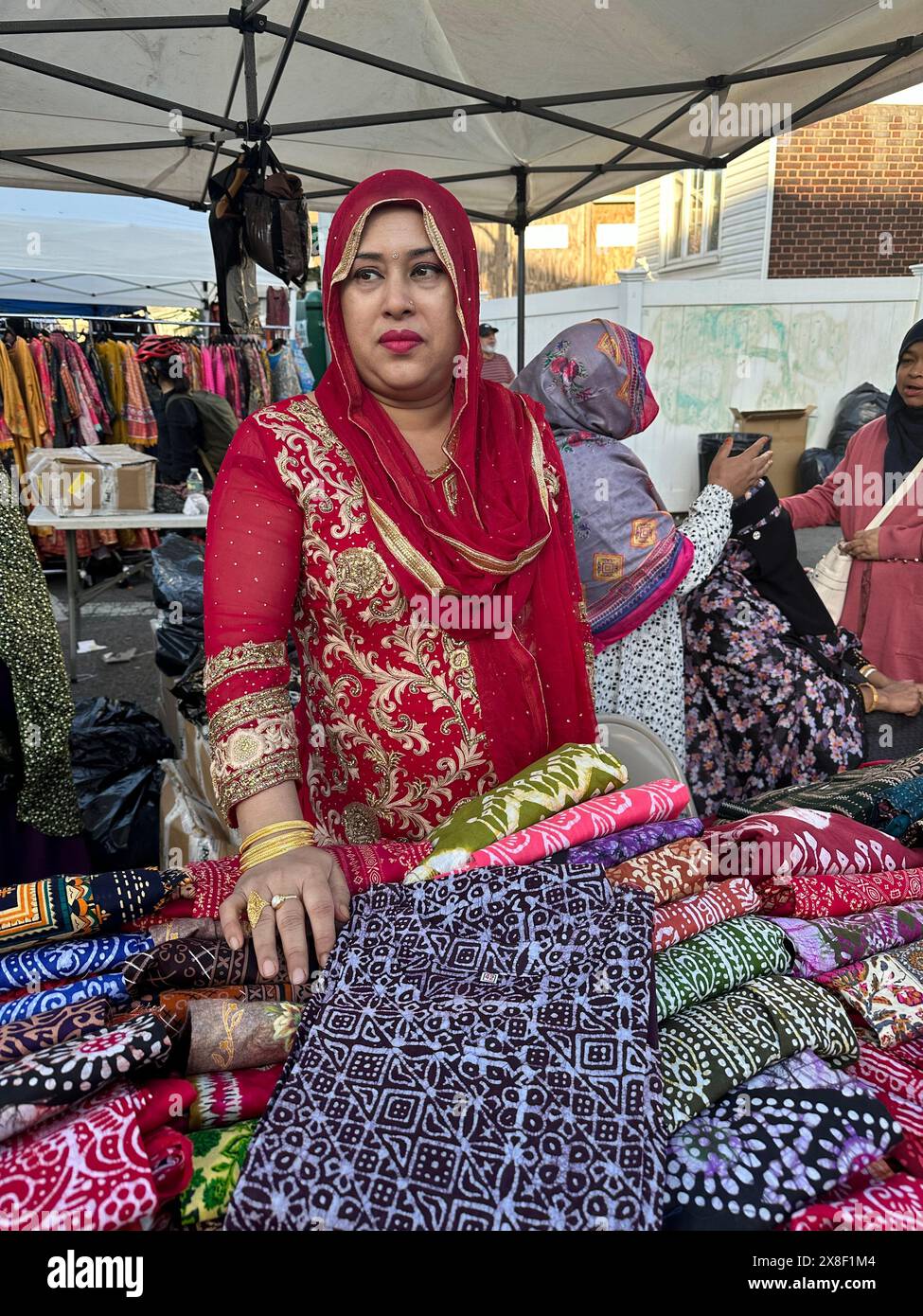 Frau, die Kleidung und Kleidung auf der Bangladeshi Street Fair im Kensington-Viertel von Brooklyn, New York, verkauft Stockfoto