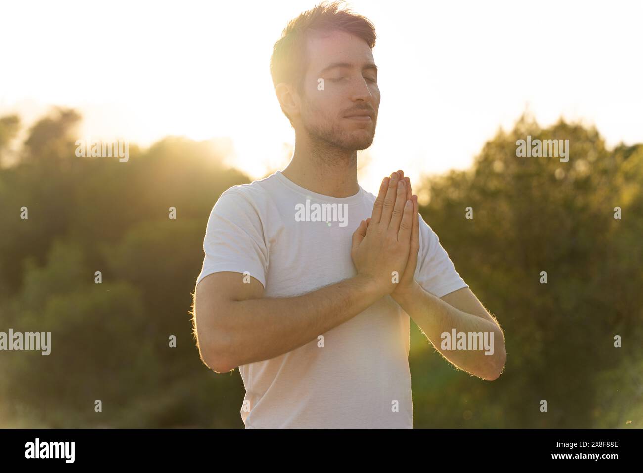 Ein Mann praktiziert Yoga in der Natur bei Sonnenuntergang Stockfoto