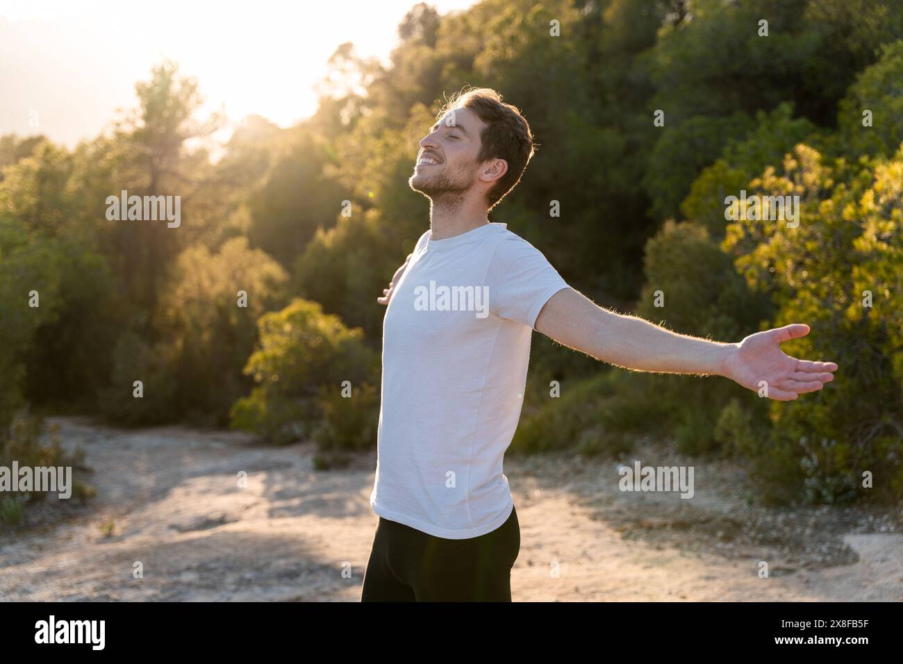 Ein attraktiver Mann atmet bei Sonnenuntergang frische Luft aus der Natur. Gesunder Lebensstil und emotionales Wohlbefinden Stockfoto