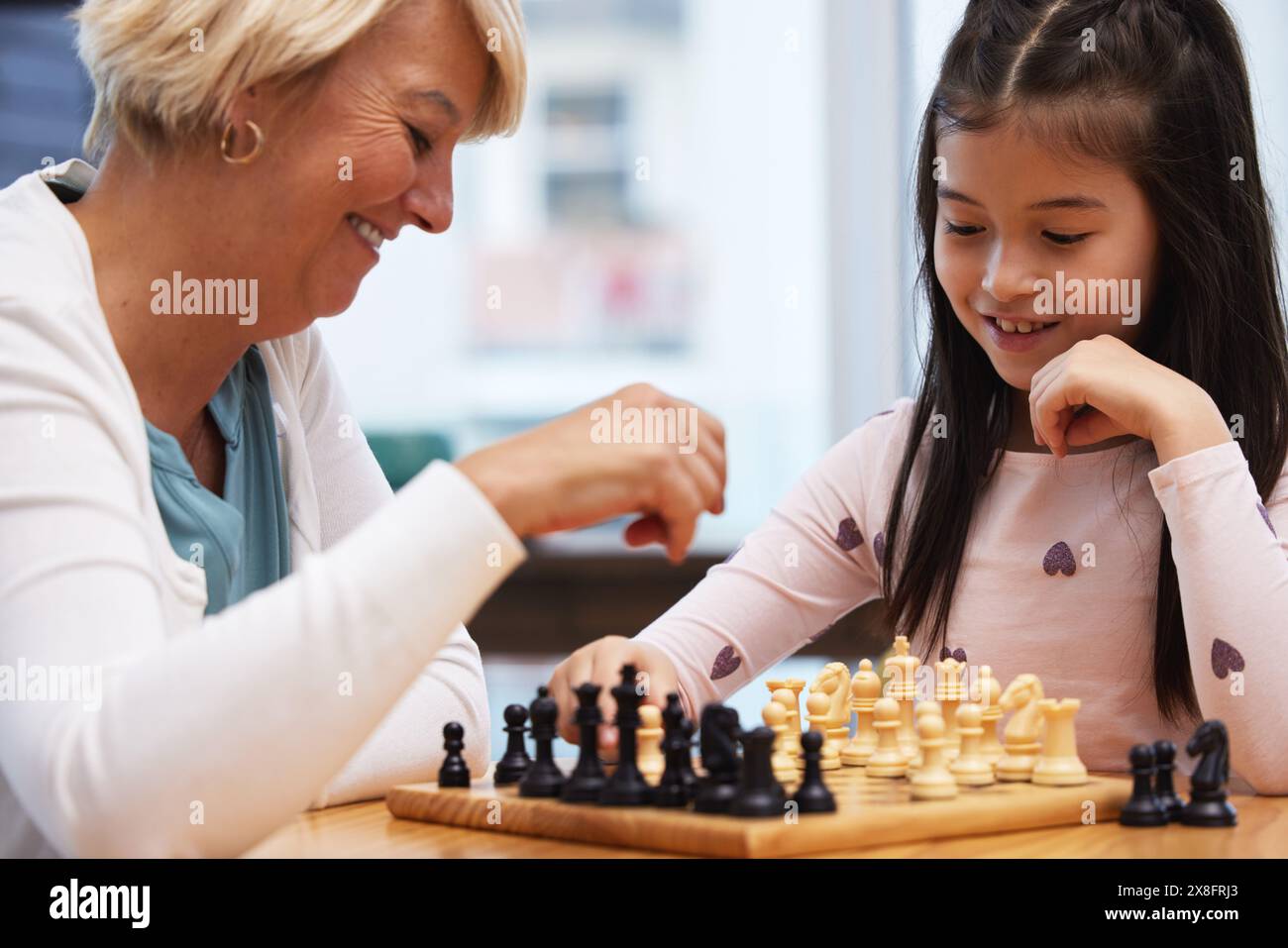 Großmutter, Mädchen und Schach lernen zu Hause, um soziale oder kritische Denkfähigkeiten, Wachstum und Entwicklung für Strategie zu spielen. Oma, Kind und Stockfoto