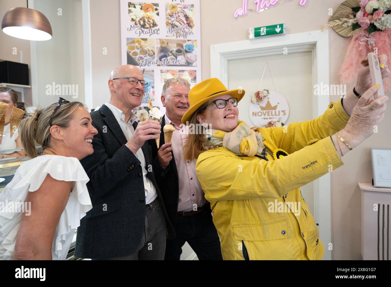 Der Vorsitzende der Scottish National Party (SNP) John Swinneyposiert für ein Selfie mit dem SNP-Kandidaten Lesley Blackhouse und dem Mitarbeiter der Novellis-Eisdiele in Burntisland, Fife, während er sich auf dem Wahlkampfpfad der General Election befindet. Bilddatum: Samstag, 25. Mai 2024. Stockfoto