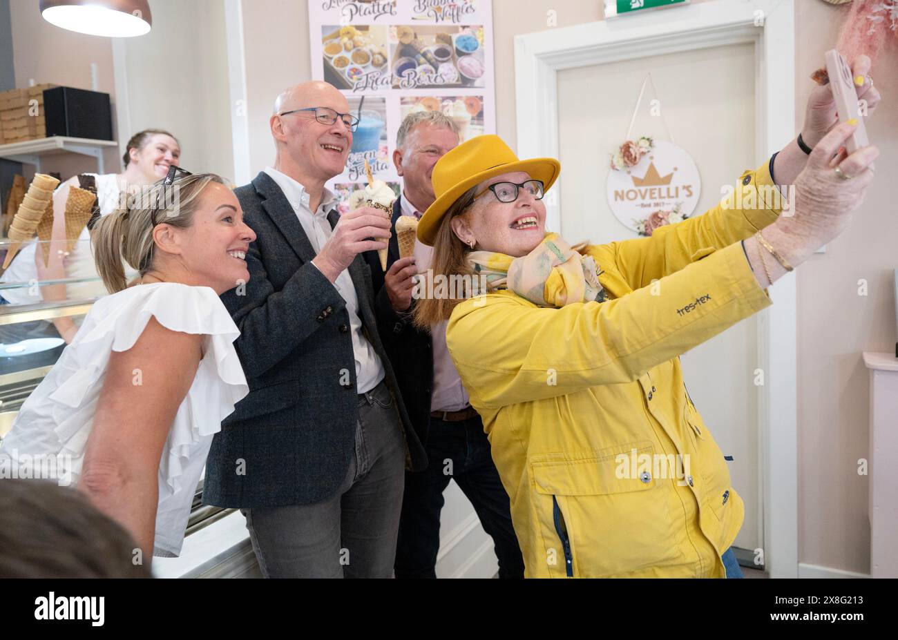 Der Vorsitzende der Scottish National Party (SNP) John Swinneyposiert für ein Selfie mit dem SNP-Kandidaten Lesley Blackhouse und dem Mitarbeiter der Novellis-Eisdiele in Burntisland, Fife, während er sich auf dem Wahlkampfpfad der General Election befindet. Bilddatum: Samstag, 25. Mai 2024. Stockfoto