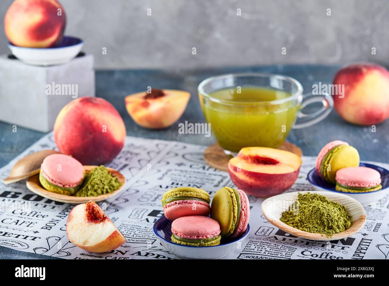 Eine köstliche Kombination aus einer Schüssel farbenfroher Macarons neben einer Tasse mit antioxidativem grünem Tee sorgt für eine perfekte Balance aus Genuss und Erfrischung Stockfoto