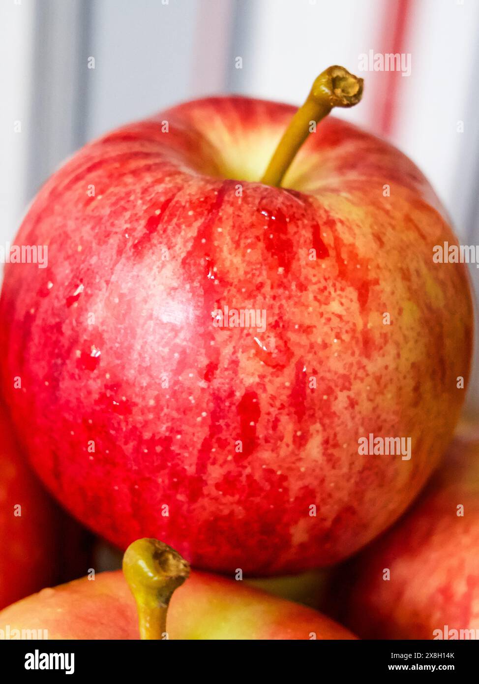 Lebendiges Apple Display. Ein leuchtender roter Apfel mit sichtbarem Stiel, ideal für kulinarische Kunst oder umweltfreundliche Lebensmittelwerbung. Stockfoto