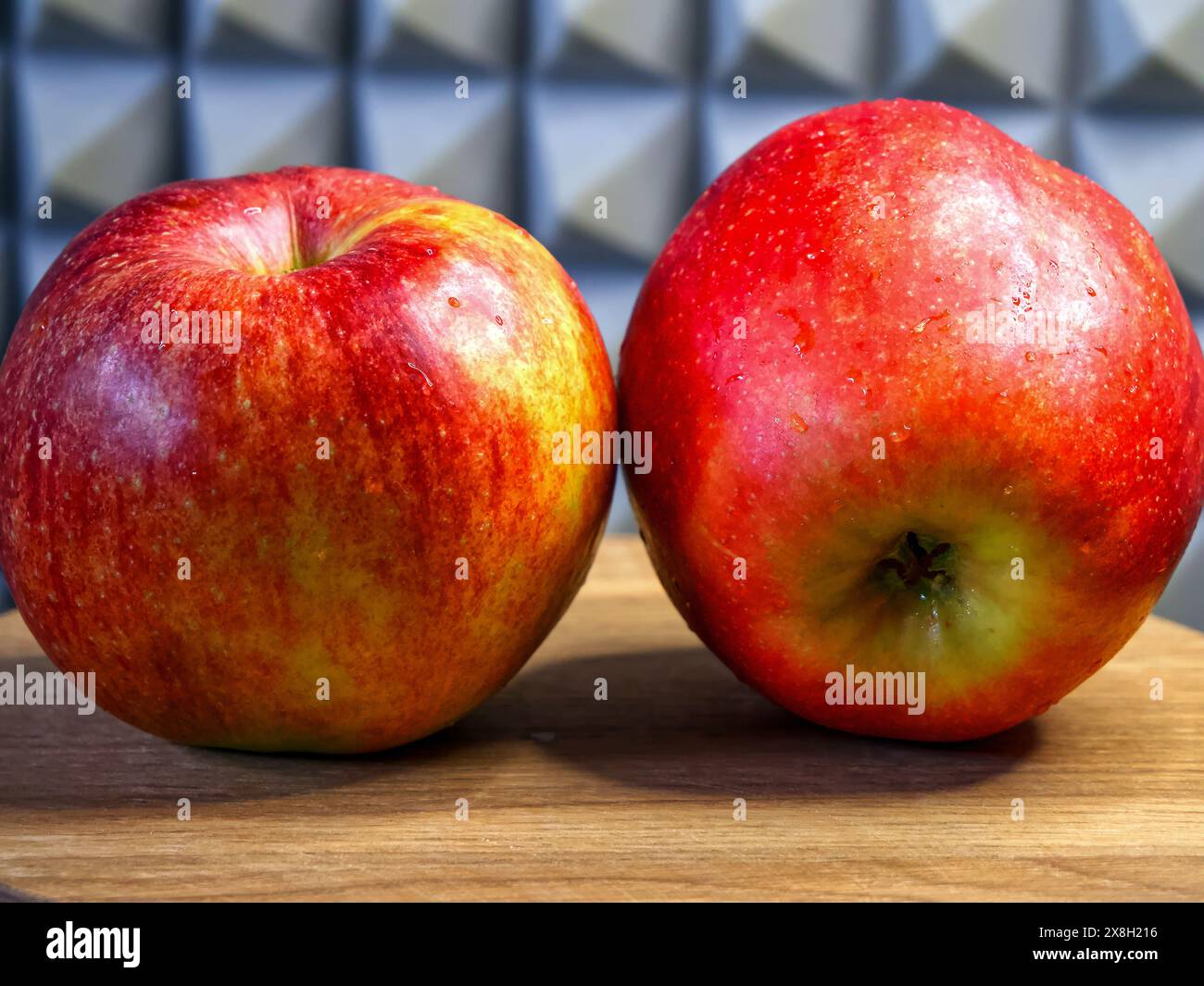 Äpfel und Kunst Rote Äpfel vor einem detaillierten Hintergrund, auf Holz platziert, für Lebensmittelwerbung. Stockfoto