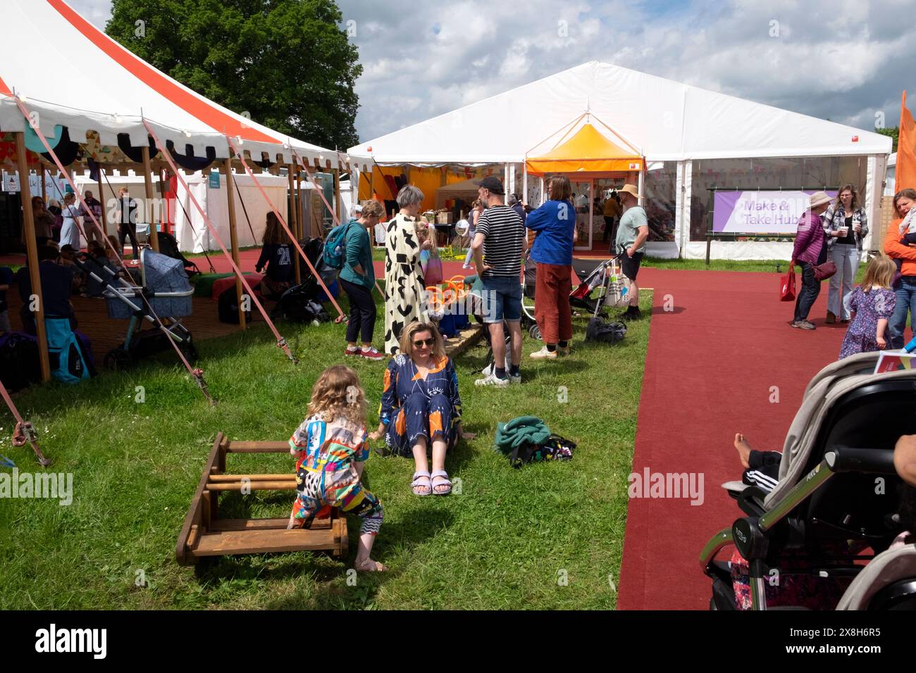 Menschen Besucher Eltern Kinder spielen im Kinderbereich vor den Marquis-Zelten beim Hay Festival Hay-on-Wye Wales 2024 UK KATHY DEWITT Stockfoto