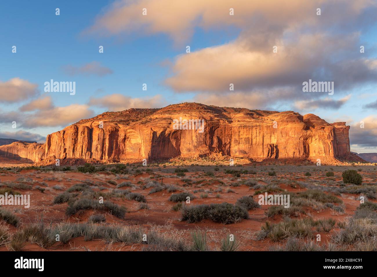 Die von der aufgehenden Sonne beleuchtete Berglandschaft wirft eine orange Farbe auf die Landschaft im Monument Valley, Arizona, ein Reiseziel für Abenteuer im Südwesten Stockfoto