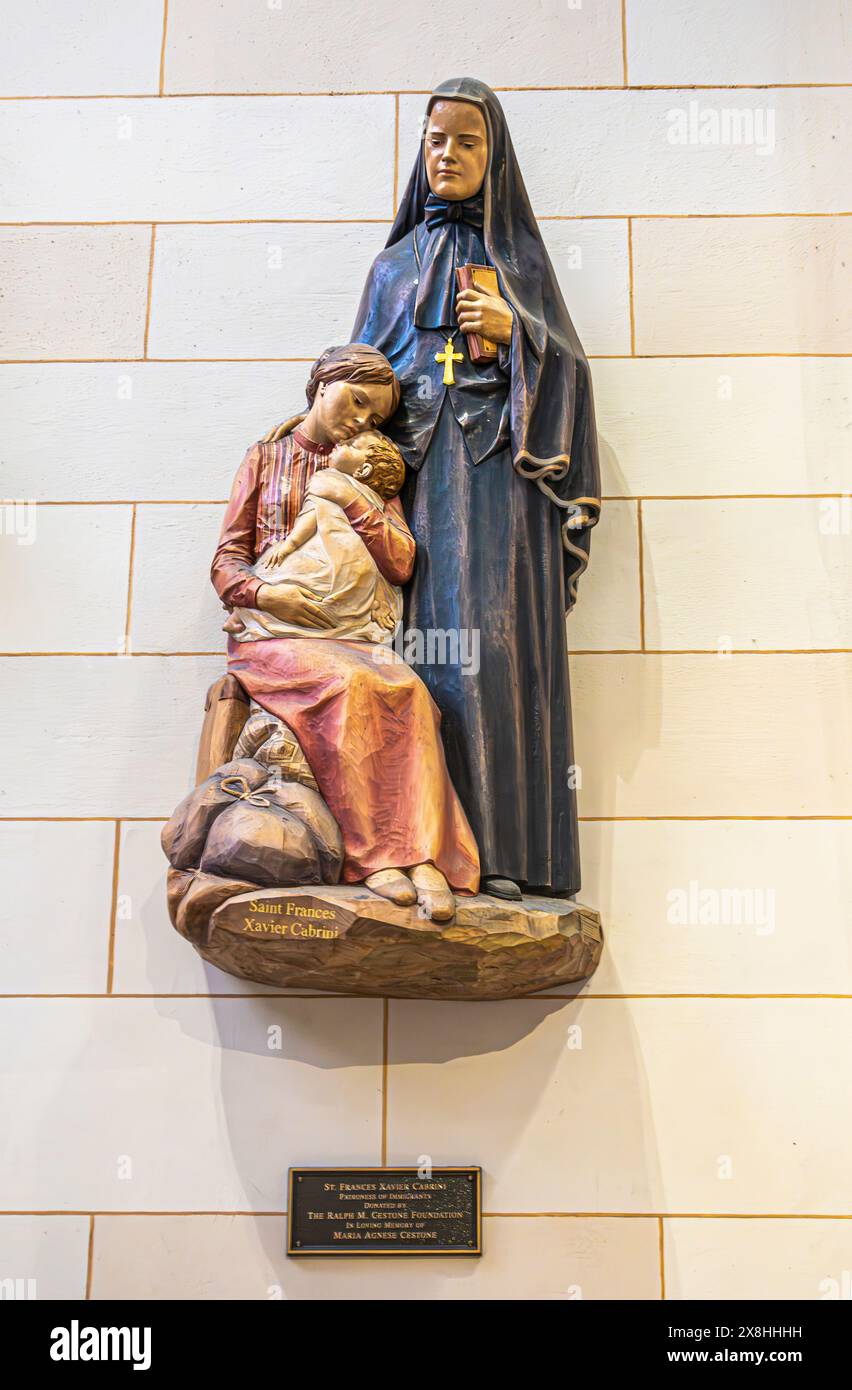 New York, NY, USA - 2. August 2023: Kleine Statue von Saint Frances Xavier Cabrini an der weißen Wand. Hat ihre Hand an der jungen Mutter und dem Kind Stockfoto