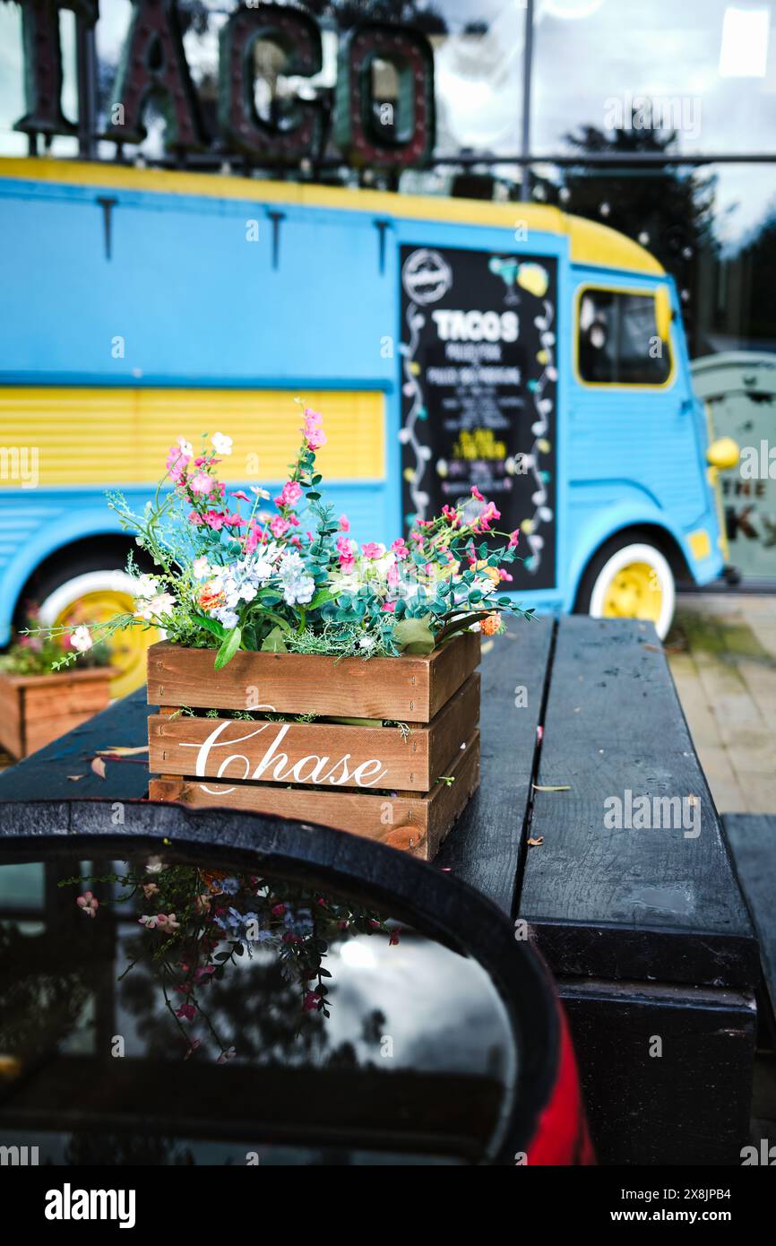 Manchester UK . Stadtleben, Blumen in Holzkiste auf rustikalem Cafétisch von blau-gelben Taco-Truck, schaffen lebendige Street Food Szene. Stockfoto