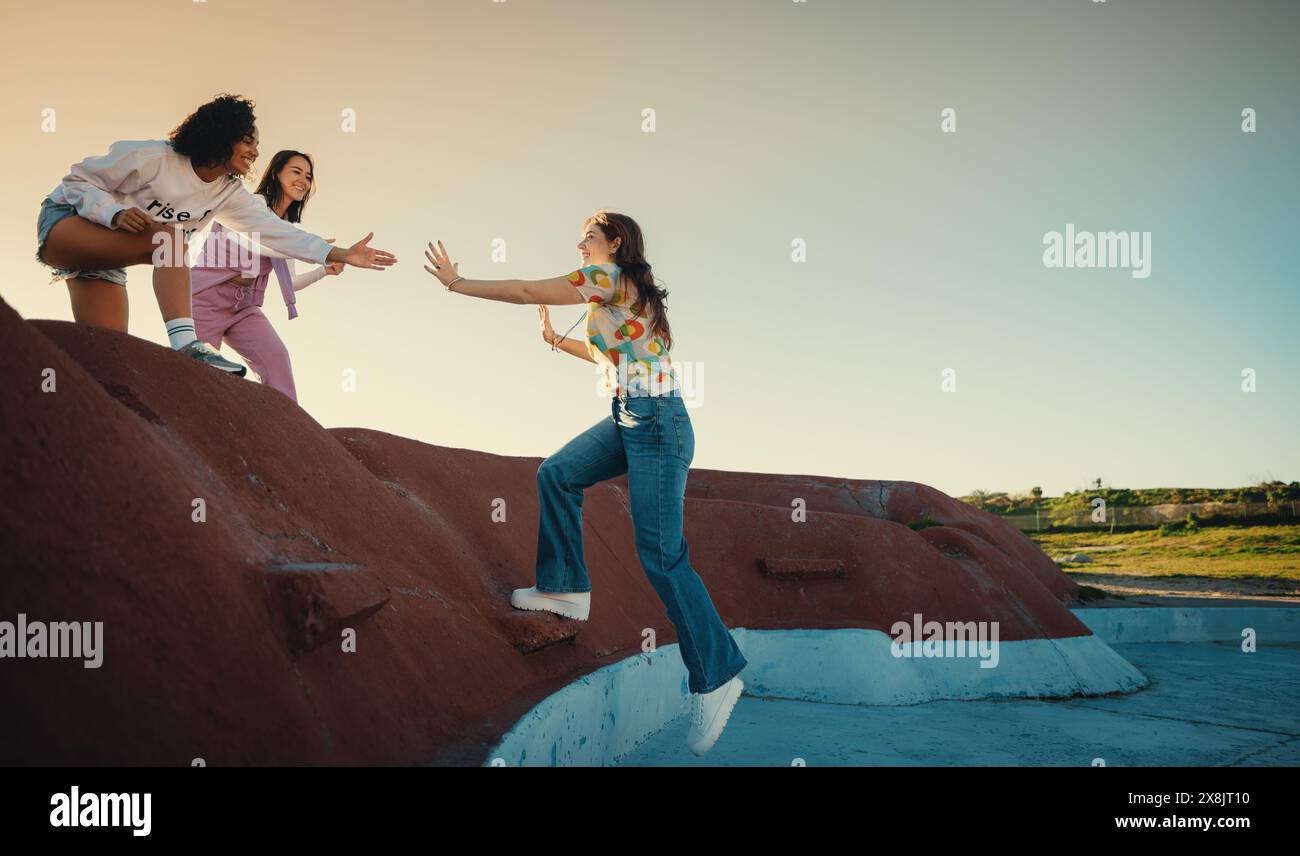 Gruppe von Freunden, die sich gegenseitig unterstützen, wenn sie in einer Umgebung im Freien auf eine Struktur klettern. Konzept von Teamarbeit, Unterstützung und Freundschaft. Stockfoto