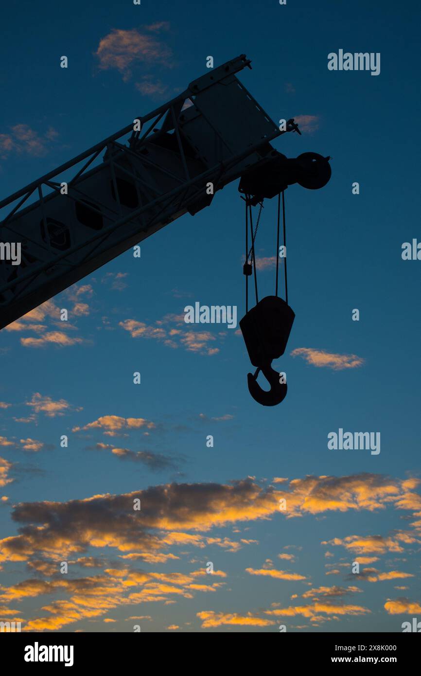 Eine Silhouettenaufnahme eines Kranhakens gegen einen blauen Himmel Stockfoto