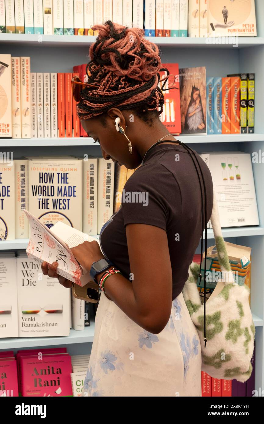 Person junge Leserin liest Bücher zum Verkauf in Bücherregalen im Buchladen beim Hay Festival 2024 Hay-on-Wye UK KATHY DEWITT Stockfoto